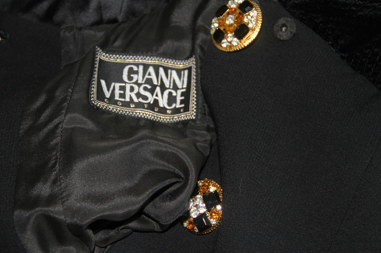 Gianni Versace black wool and silk cocktail coat dress from the Fall 1991 collection.

The coat dress features embroidery to the pockets, together with a series of oversized gold tone metal and paste buttons.

Marked an Italian size