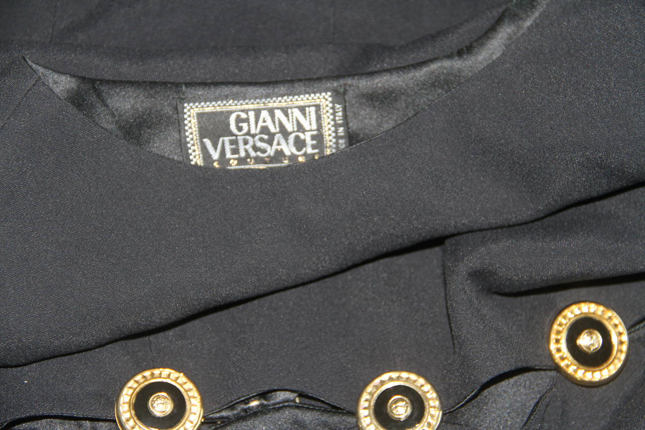 Gianni Versace black silk crepe sleeveless shift dress with cut-out slits across the waist and hem, secured by gold and black Medusa embossed medallions from the Fall 1994 collection.

Marked an Italian size 40.

Fabric content - 16% silk 40%