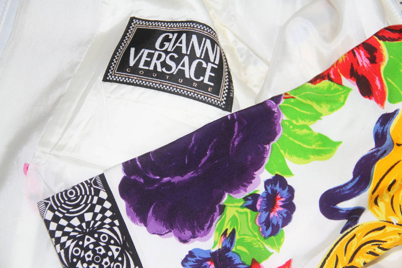 Gianni Versace white and floral printed silk and cotton zip front jacket from the Spring 1992 collection. 

The print features gilt Baroque shoulders and a lilac rose motif. The jacket also features optical printed silk sleeve inserts and edging