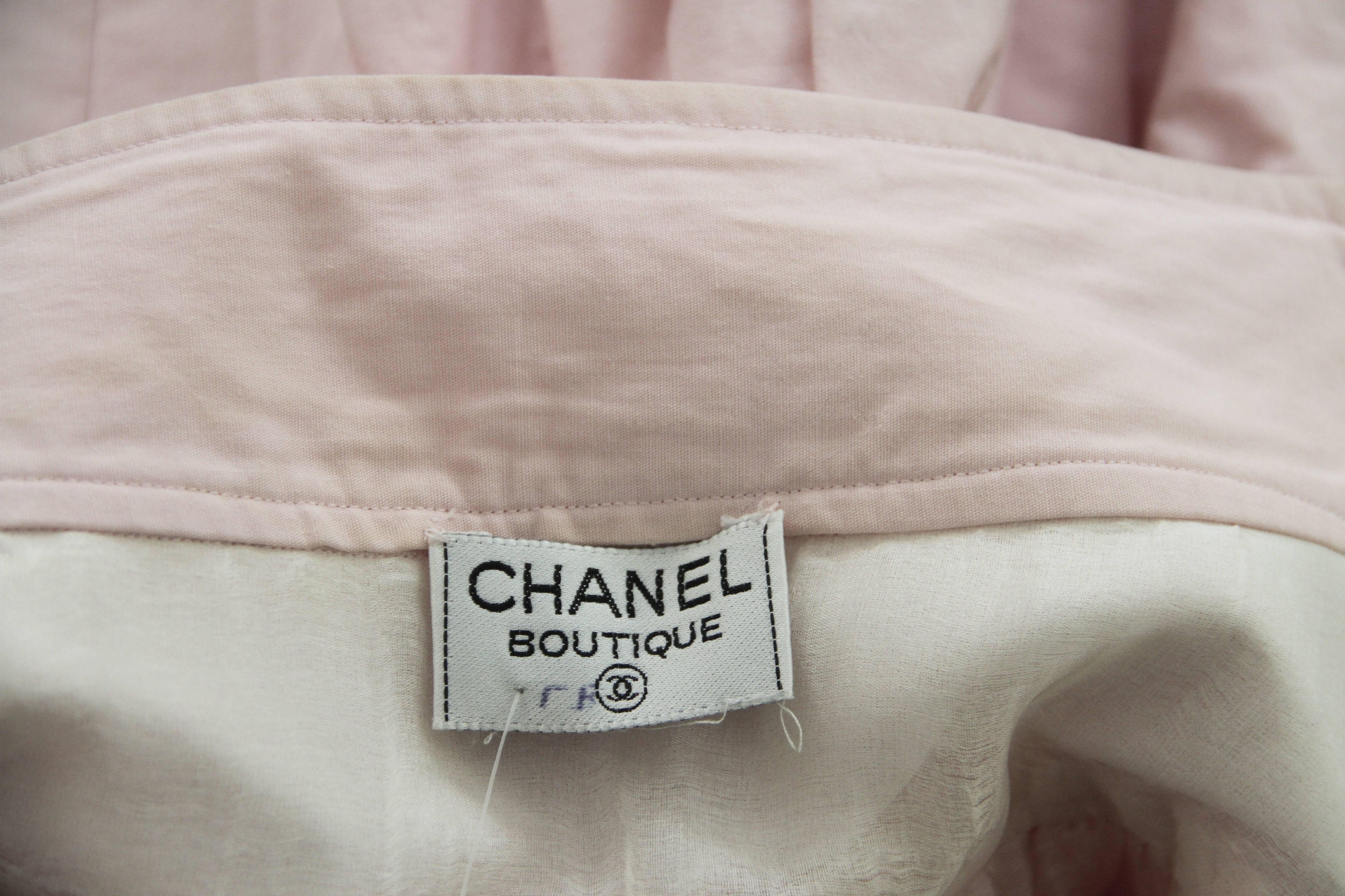 Chanel baby pink cotton tiered ruffle skirt from the late 1980's. The skirt features gold-tone metal Chanel logo buttons to each side.

Marked an French size 38.