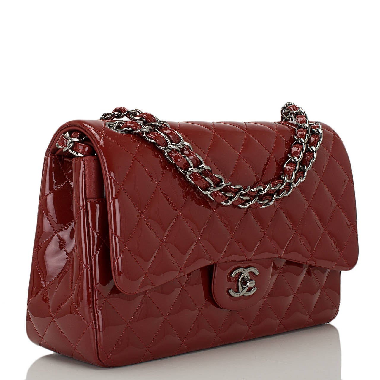 Chanel Jumbo Classic double flap of dark red patent leather with ruthenium hardware.

This bag features a front flap with signature CC turnlock closure, a half moon back pocket, and an adjustable interwoven silver tone chain link with red leather