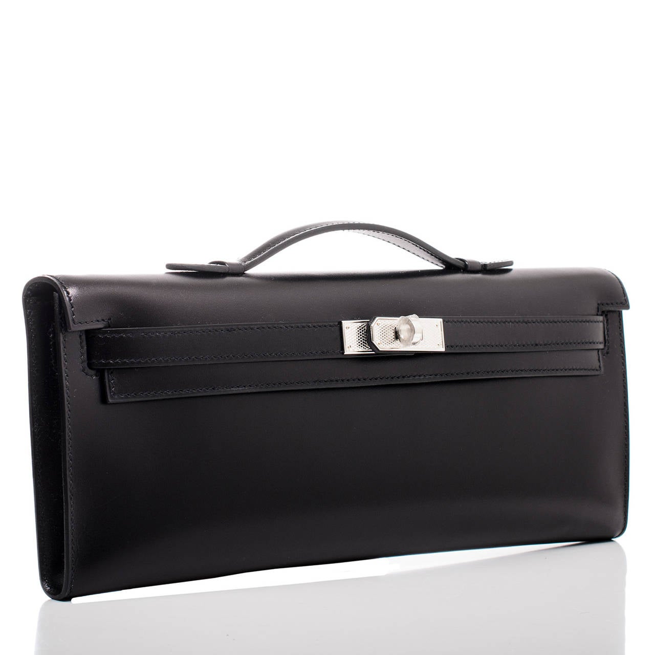 Hermes Black Kelly Cut clutch in box (smooth calfskin) leather with palladium guilloche hardware.

Hermes introduced the Kelly Cut in the fall/winter collection in 2006. The long, sleek lines with the small handle accented by the iconic Kelly