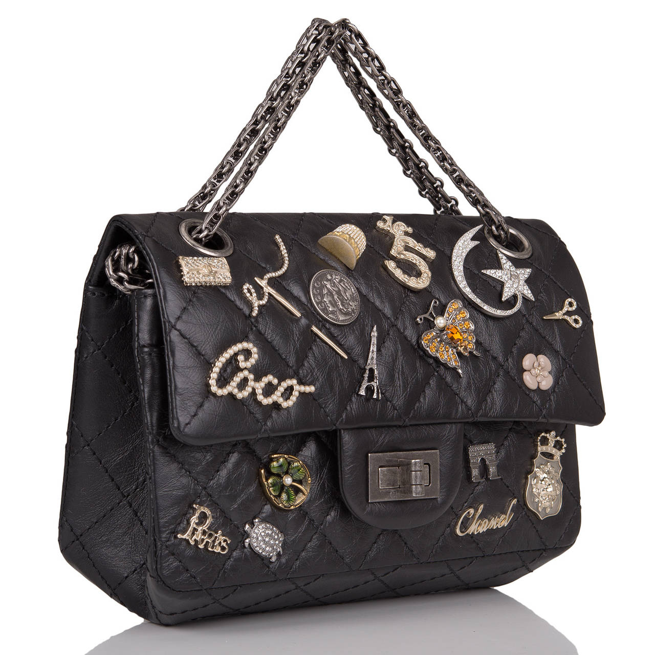 This Limited Edition Chanel Lucky Charm Reissue 2.55 bag in black aged calfskin leather with aged ruthenium hardware in size 224. This embellished Chanel bag features 21 iconic Chanel charms, front flap with Mademoiselle turnlock closure, a half
