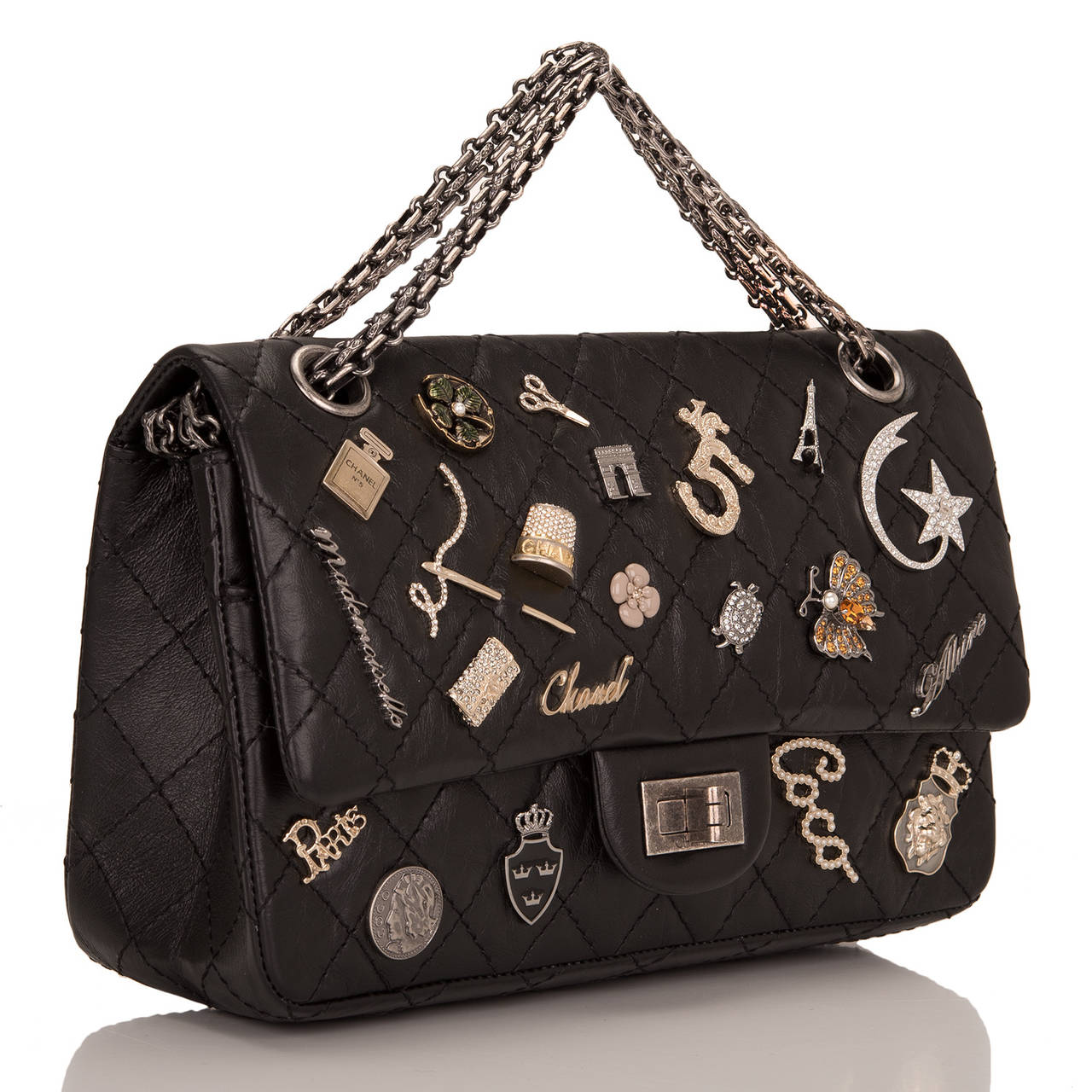 This Limited Edition Chanel Lucky Charm Reissue 2.55 bag in black aged calfskin leather with aged ruthenium hardware in size 225. This embellished Chanel bag features 21 iconic Chanel charms, front flap with Mademoiselle turnlock closure, a half