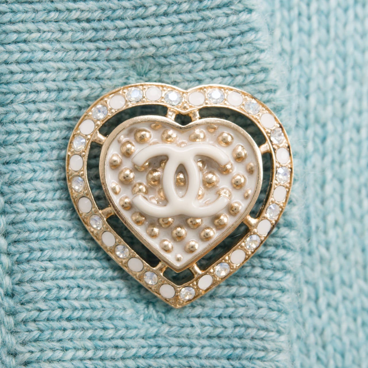 Chanel seafoam green cashmere sweater coat with round neckline, six CC-stamped jewel and enamel silver tone heart buttons, hip level patch pockets, and vertical ribbed trimming  at pockets, cuff, and bottom.
 
Fabric: 100% cashmere
 
Collection: