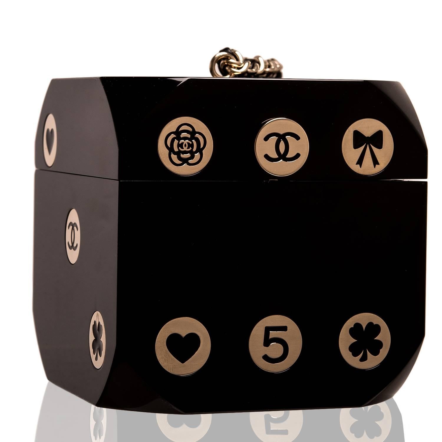 Chanel limited edition, runway Casino Dice minaudiere of black PVC with brass hardware.

This rare, collectible clutch shaped like a single die features lucky club and heart symbols, Chanel icon No. 5, CC logo and camellia charms in brass in a