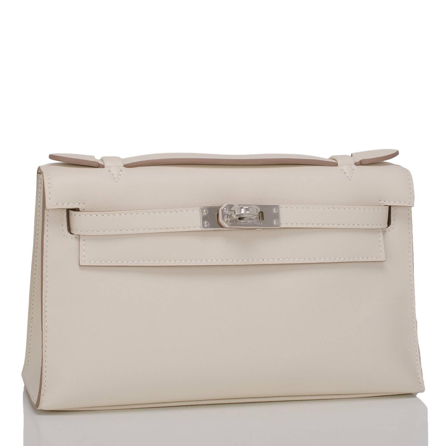 Hermes Craie Mini Kelly Pochette in swift leather with palladium hardware.

This Hermes Kelly Pochette has tonal stitching, a front flap with two straps, a toggle closure and a single flat handle.

The interior is lined with craie chevre and has