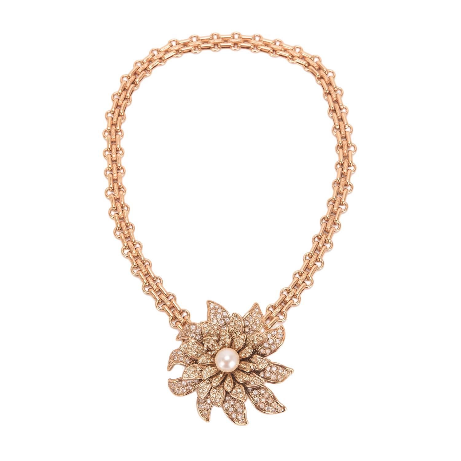 Chanel gold tone choker with large rhinestone embedded gold tone camellia flower pendant with CC logo and large faux pearl at center and hidden hook closure.

Collection: 05A

Condition: Mint

Accompaned By: Chanel box and