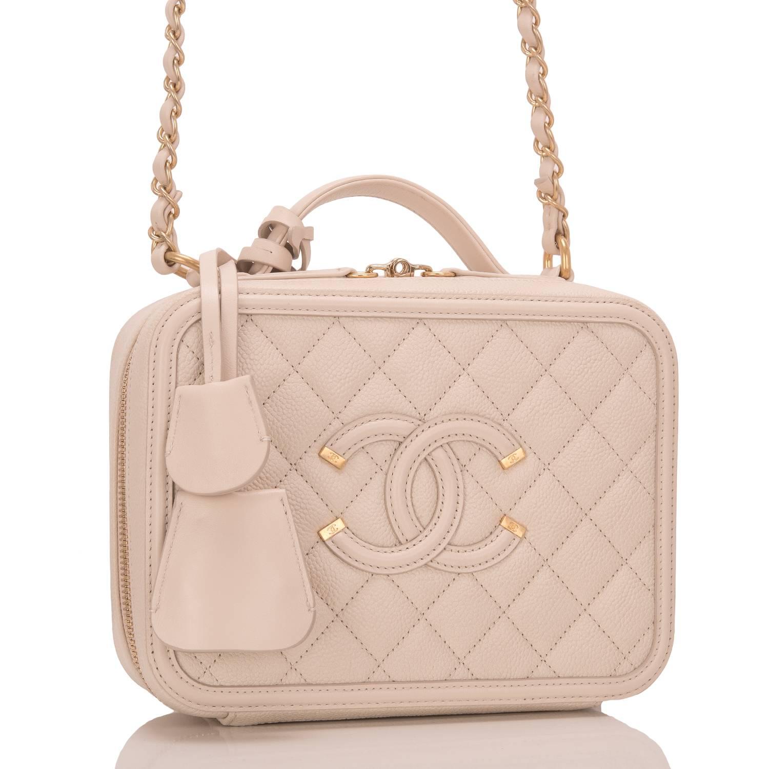 Chanel Small Filigree Vanity Case of light beige caviar leather with gold tone hardware.

This bag features Chanel's signature CC logo stitch in on the front, a gold tone CC lock with a clochette, a matching key with another clochette, zip around