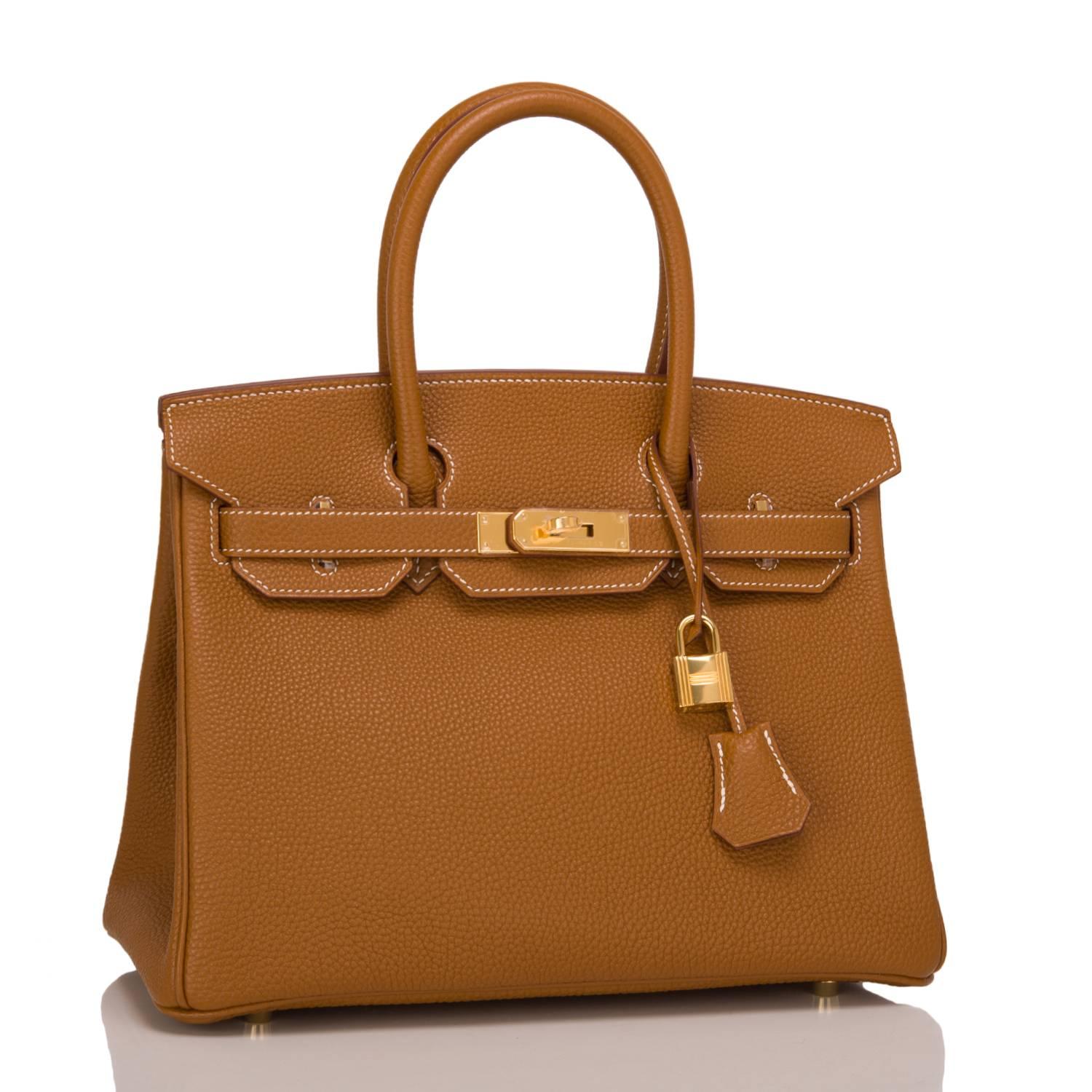 Hermes Gold Birkin 30cm in togo leather with gold hardware.

This Birkin features white contrast stitching, a front toggle closure, a clochette with lock and two keys, and double rolled handles.

The interior is lined with Gold chevre and has