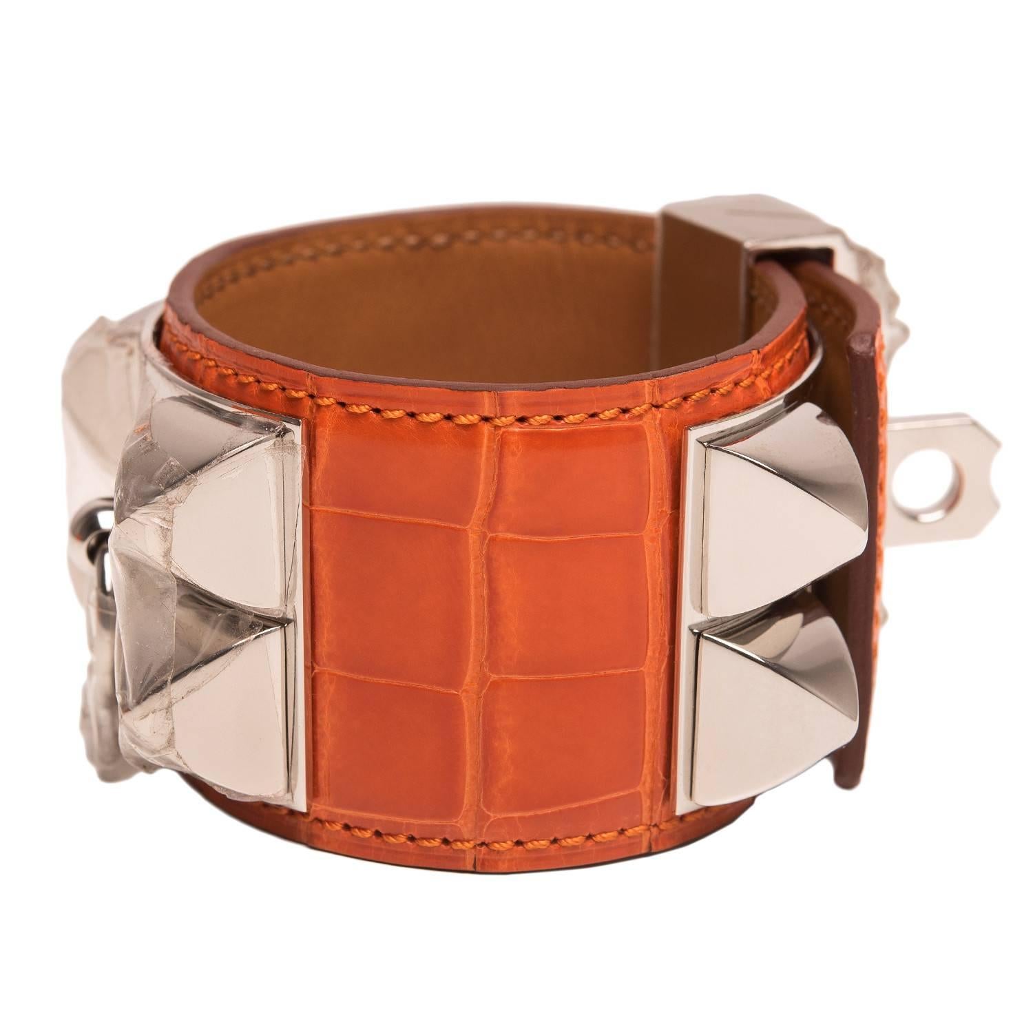 Hermes Collier de Chien (CDC) in Orange shiny alligator with palladium plated hardware in size small.

This style features palladium pyramid studs, center ring and adjustable push lock closure.

Collection: P Square

Origin: