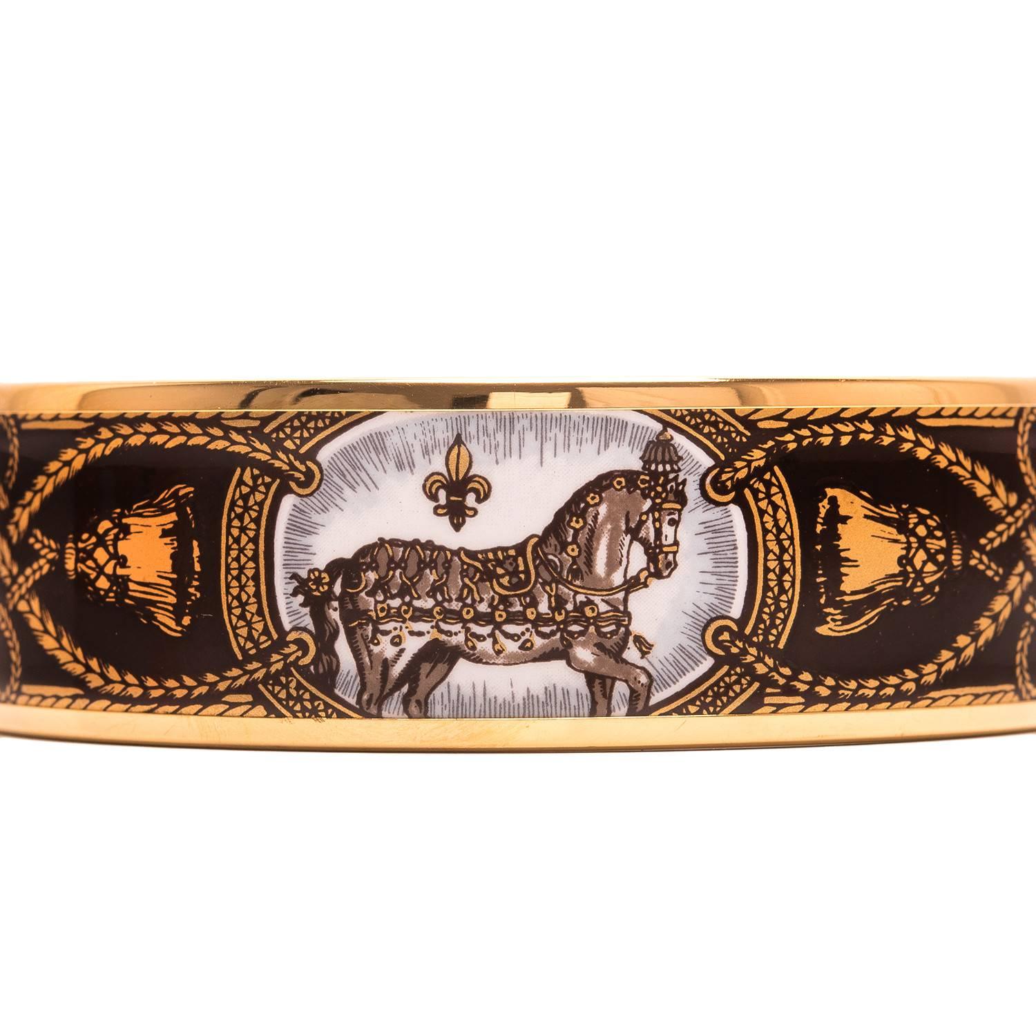 Hermes "Grand Apparat" wide printed enamel bracelet in size GM (70).

This bracelet depicts horses in royal costume on a purple colored background with gold plated hardware.

Origin: Austria

Condition: Excellent

Accompanied by: