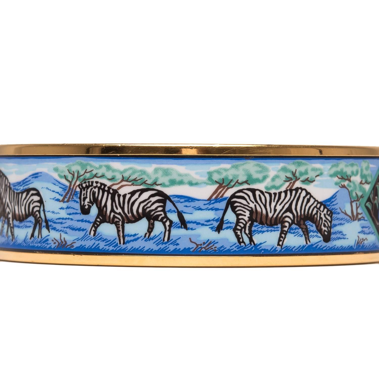 Hermes "Zebras" wide printed enamel bracelet size GM (70).

This bracelet depicts a zebra safari on a blue colored background with gold plated hardware.

Origin: Austria

Condition: Excellent 

Accompanied by: Hermes box

Size: