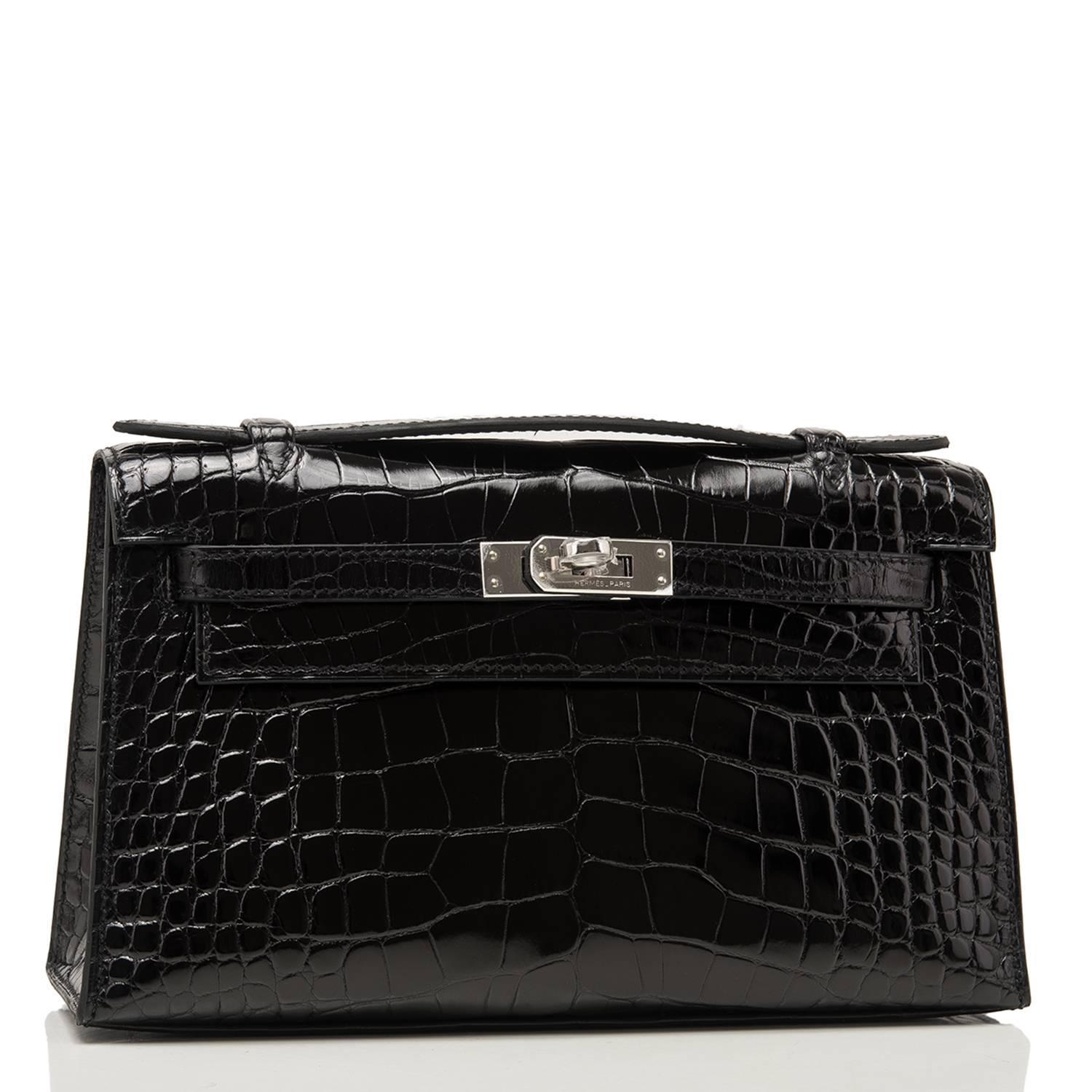 Hermes Black Mini Kelly Pochette clutch of shiny alligator with palladium hardware.

This Hermes Kelly Pochette a front flap with two straps, a toggle closure and a single flat handle.

The interior is lined with black chevre and has one wall
