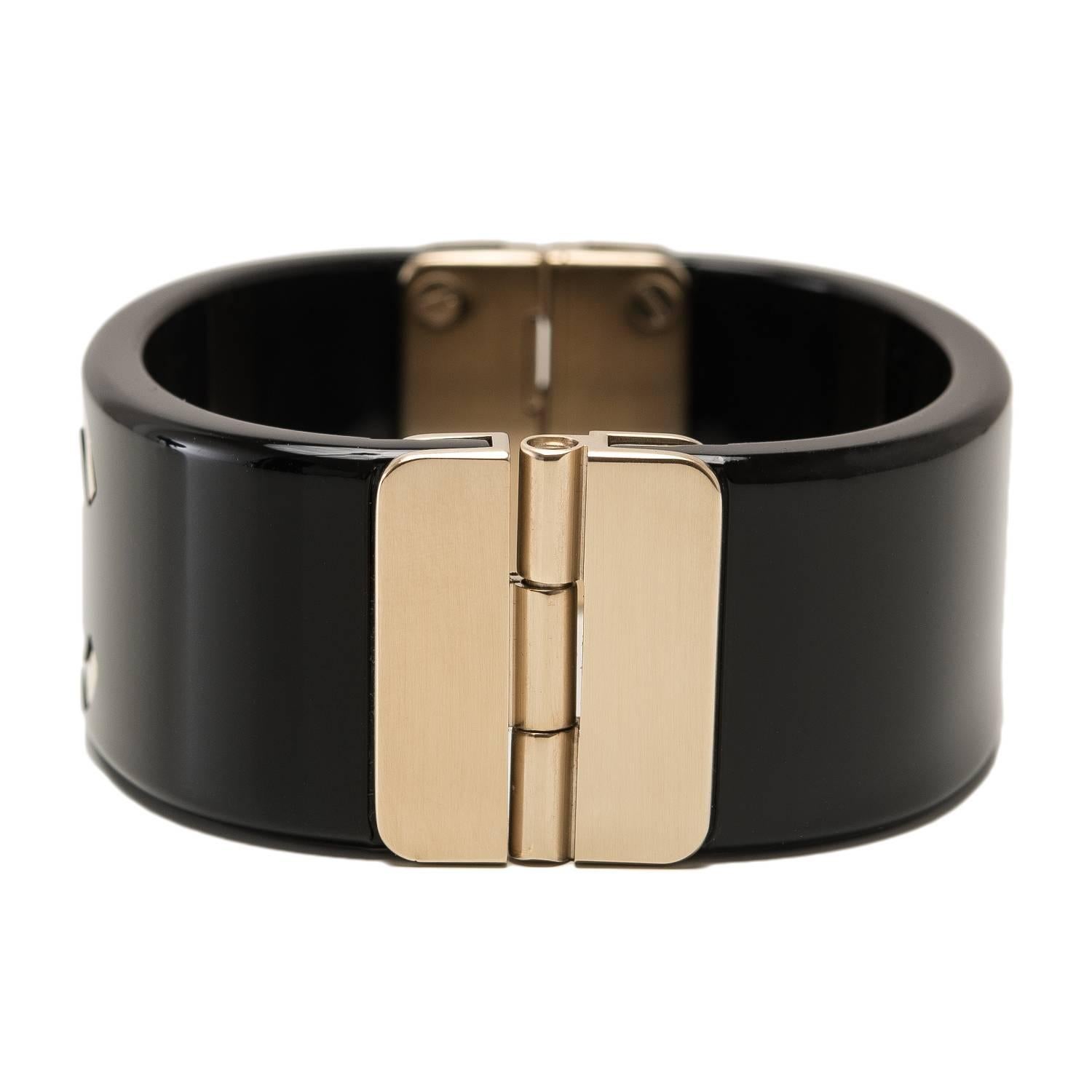 Chanel wide CC logo cuff bracelet of black resin and matte gold tone metal.

This limited edition bracelet, part of the Spring 2016 collection, has a CC-logo in front, a matte gold tone hinge closure in back and matte push button