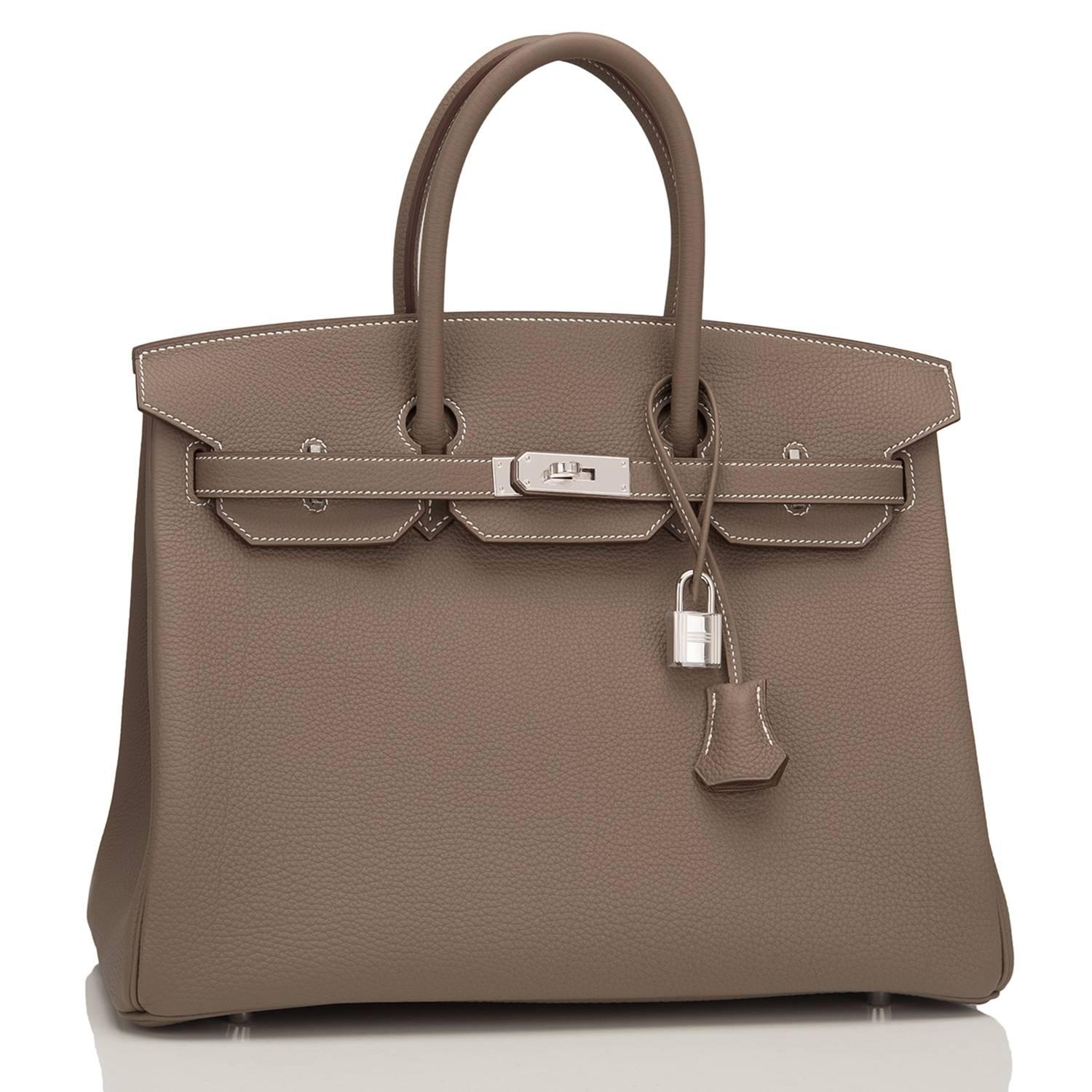 Hermes Etoupe Birkin 35cm of togo leather with palladium hardware.

This Birkin has white contrast stitching, a front toggle closure, a clochette with lock and two keys, and double rolled handles.

The interior is lined with Etoupe chevre and