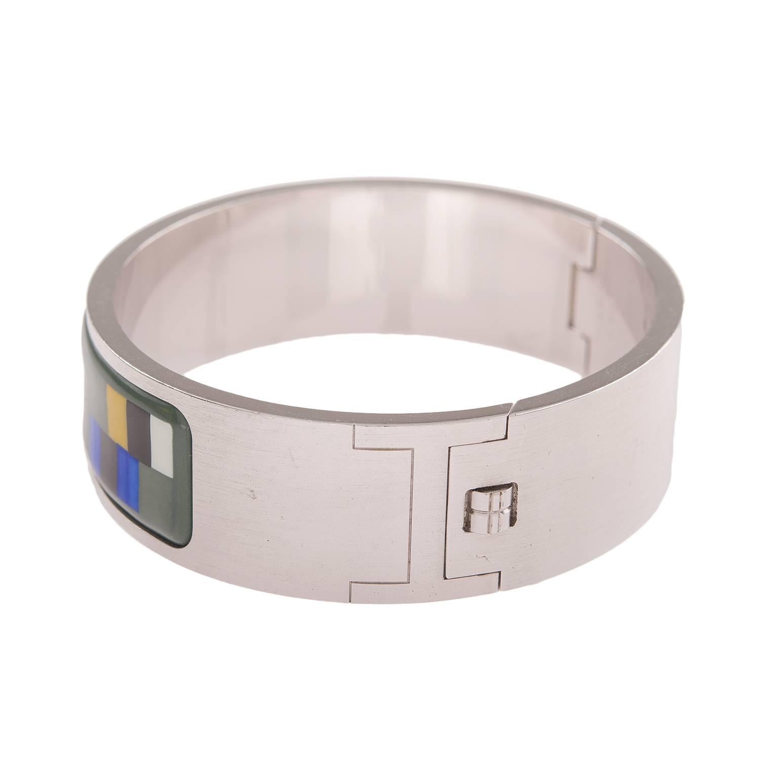 Hermes vintage printed enamel bracelet size PM (65).
 
This bracelet depicts multi-color color blocks on a green background with stainless steel hardware.

Origin: France
 
Condition: Excellent; minor scratches, retains shiny hardware
 
Accompanied
