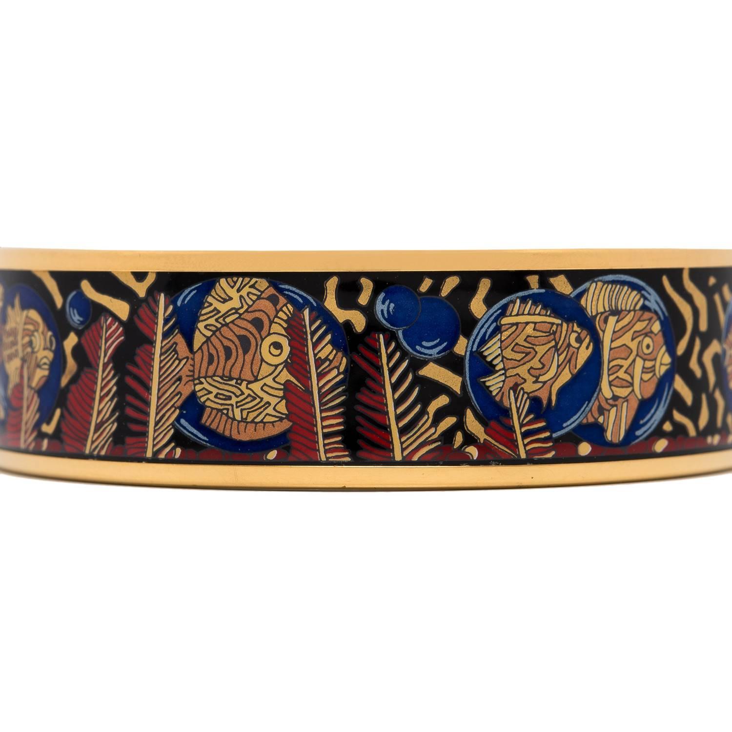 Hermes "Fishes and Ferns" wide printed enamel bracelet size PM (65).
 
This bracelet depicts fish and ferns on a black colored background with gold plated hardware.

Origin: Austria
 
Condition: Vintage; excellent  
 
Accompanied by: