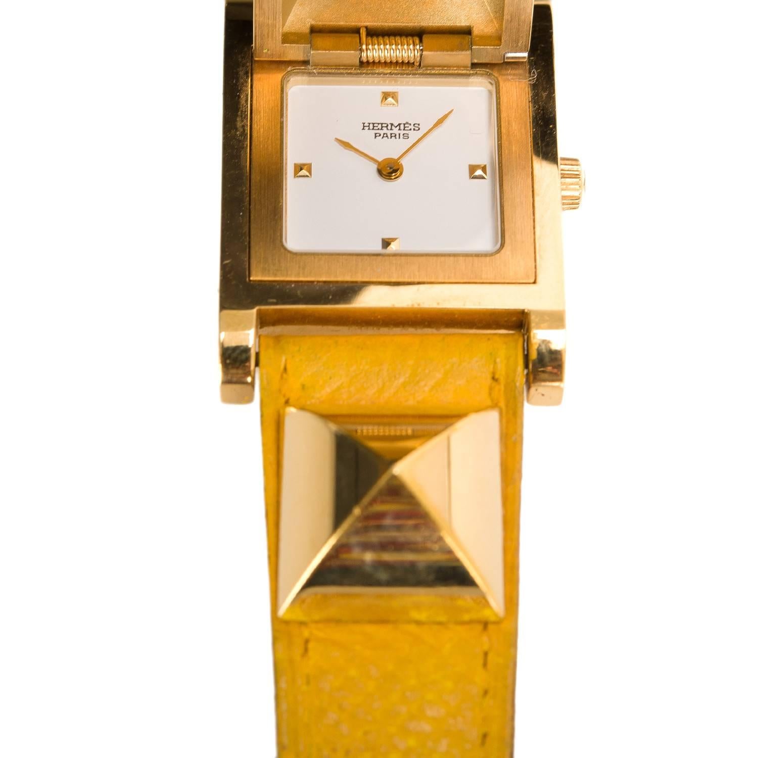 Hermes Medor watch in yellow courcheval in a size PM.

This stunning style made of gold plated stainless steel features swiss quartz movement, white dial, sapphire crystal push-pull crown, and adjustable Yellow courcheval band with an Hermes stamped