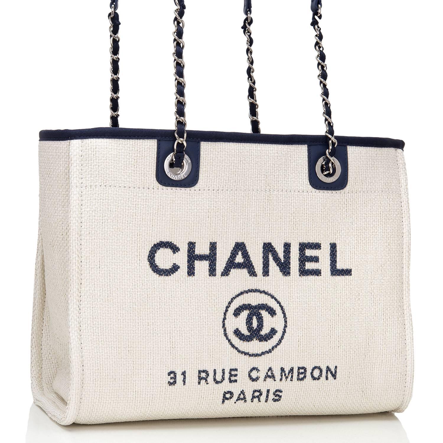 Chanel Small Deauville Canvas Tote of white canvas, navy leather trim and silver tone hardware.

This bag features the signature CC logo in a circle with the brand CHANEL above it and the Paris flagship store address -- 