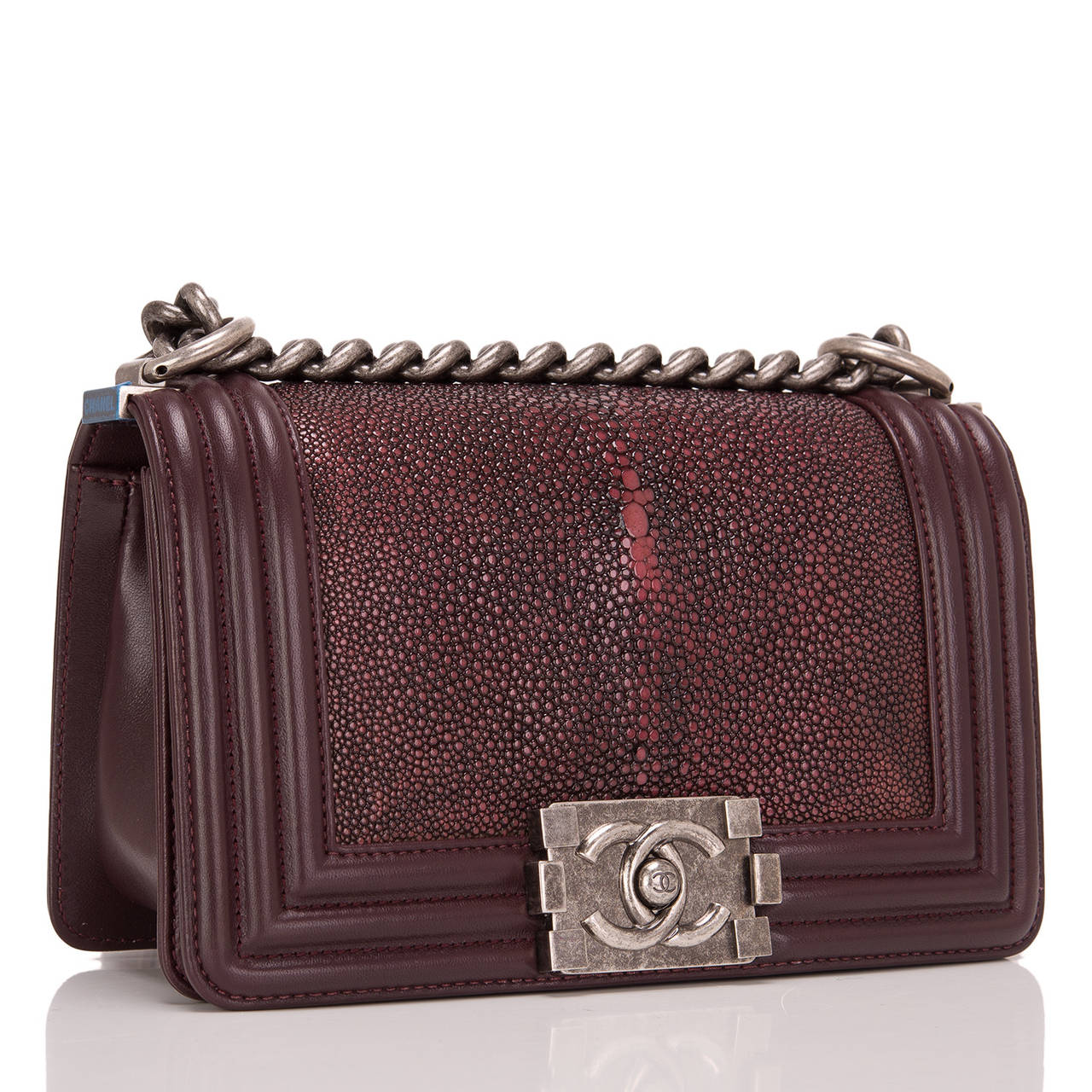 This limited edition Small Boy bag is exceptional in burgundy stingray, accented by burgundy lambskin leather and aged ruthenium hardware. The bag has a full front flap with the Boy Chanel signature CC push lock closure and aged ruthenium chain link