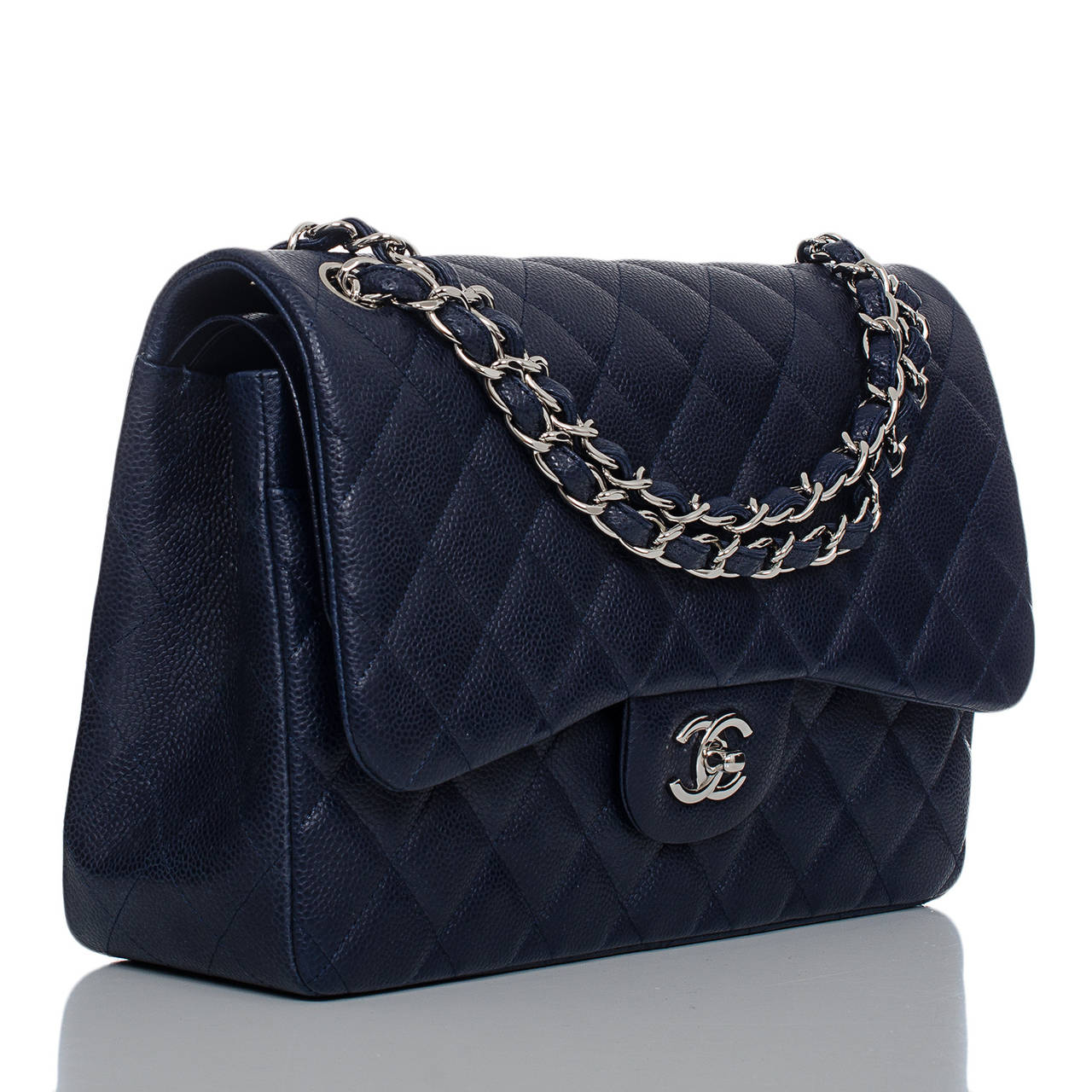 This Chanel Jumbo Classic double flap of navy caviar leather with silver tone hardware features a front flap with signature CC turnlock closure, half moon back pocket, and an adjustable interwoven silver tone chain link and navy leather shoulder