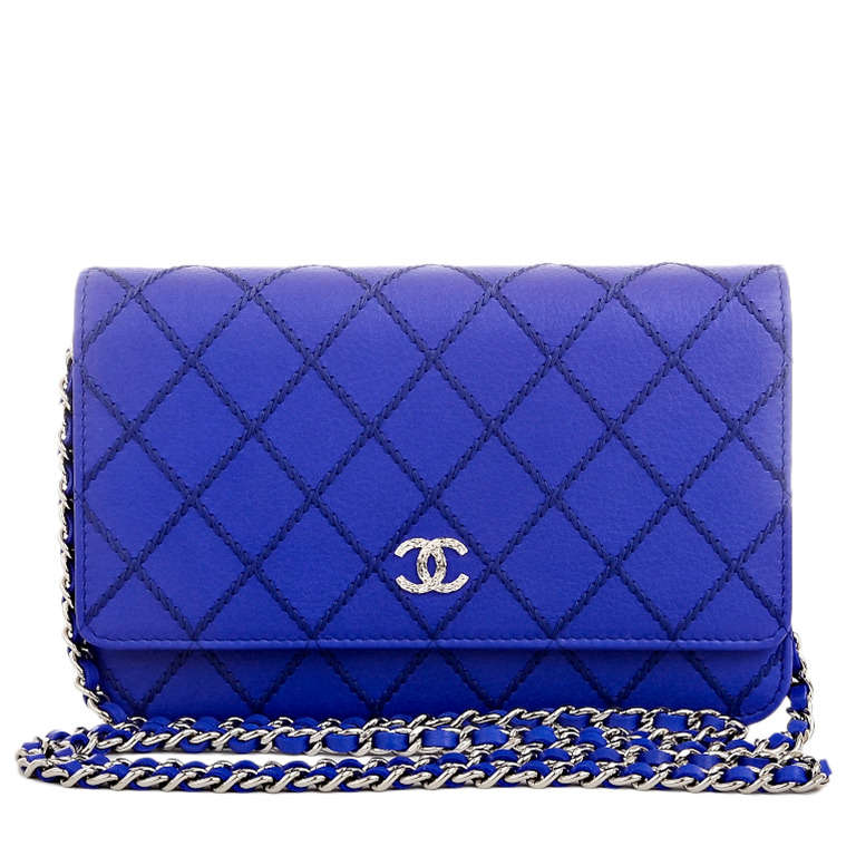 Chanel royal blue quilted calfskin leather wallet on chain (WOC) with silvertone hardware, front flap with textured CC charm and hidden snap closure, expandable sides and bottom, and interwoven silvertone chain link and blue leather