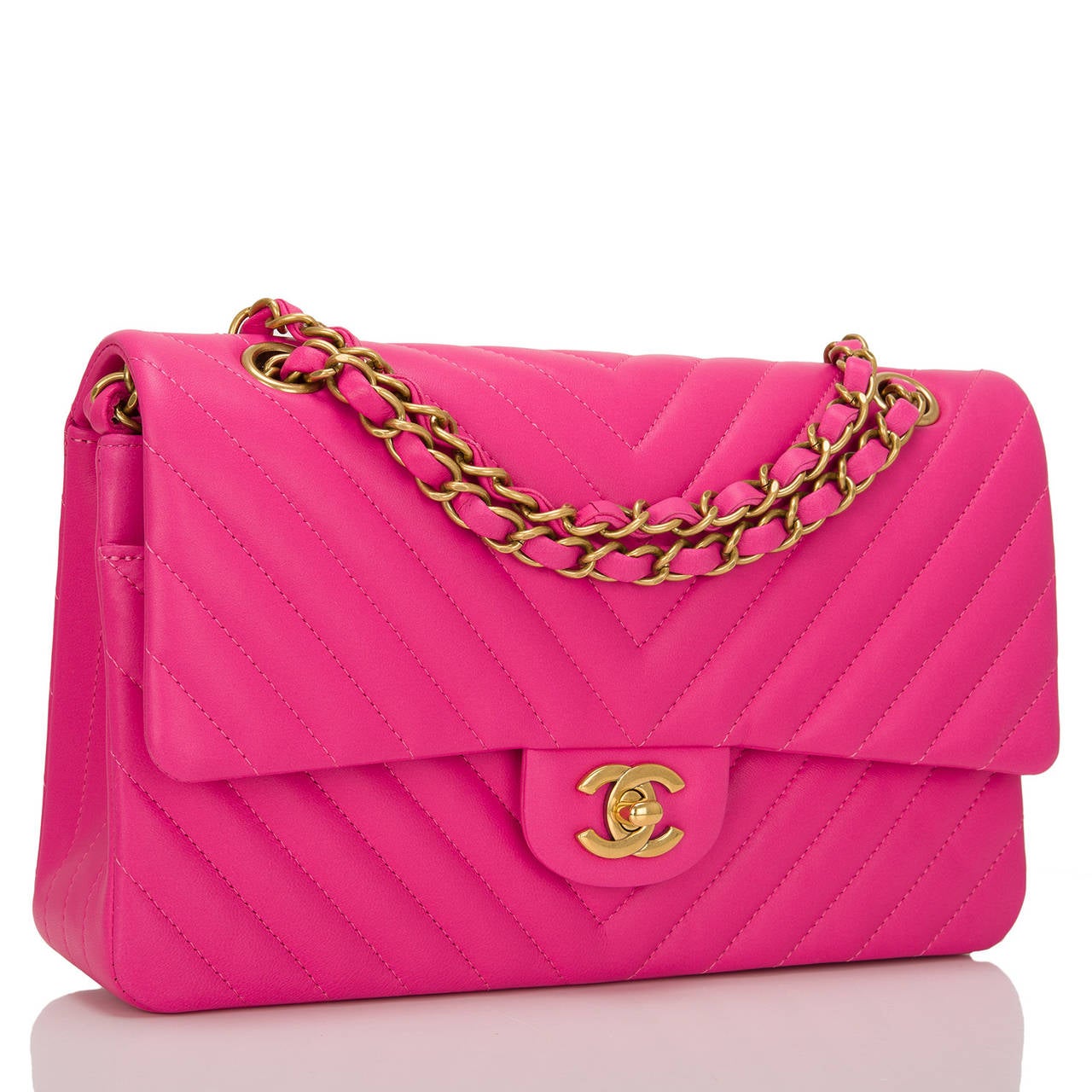 This limited edition Chanel Fuchsia Chevron Medium classic double flap bag in fuchsia lambskin leather and aged gold tone hardware is an edgy take on the iconic Chanel Classic bag. It features a front flap with signature CC turnlock closure, half