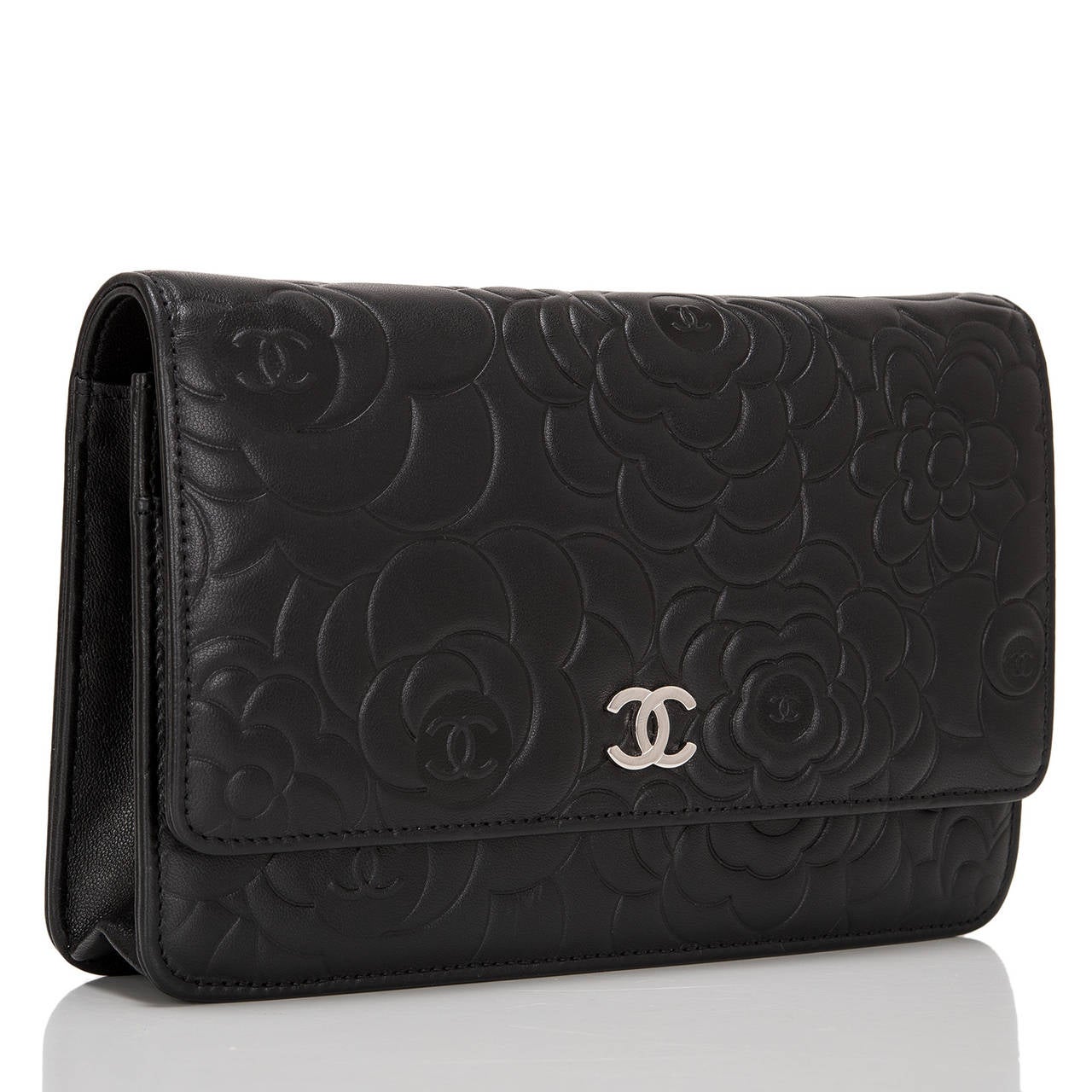 This black Camellia Wallet on Chain (WOC) of lambskin leather with silver tone hardware features an embossed camellia flower pattern, front flap with CC charm and hidden snap closure, smooth expandable black leather sides and bottom and interwoven