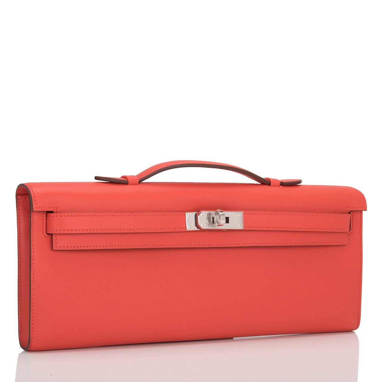 This Hermes Kelly Cut in Capucine is a gorgeous red color with palladium hardware; the bag has tonal stitching, front straps with toggle closure and a top flat handle.

The interior is lined in Capucine chèvre leather and features an open wall
