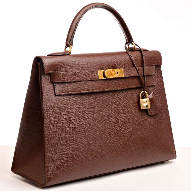 Hermes Chocolat courchevel leather Kelly 32cm with tonal stitching, gold hardware, front toggle closure, clochette with lock and two keys, single rolled handle and removable shoulder strap. Interior is lined in Chocolat chevre and features: one zip