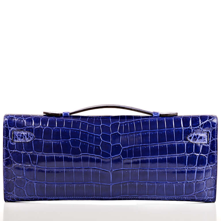 Hermes Bleu Electrique shiny niloticus crocodile Kelly Cut clutch with tonal stitching, permabrass hardware, front straps with toggle closure and top flat handle. Interior is lined in Bleu Electrique chevre and features: one open wall
