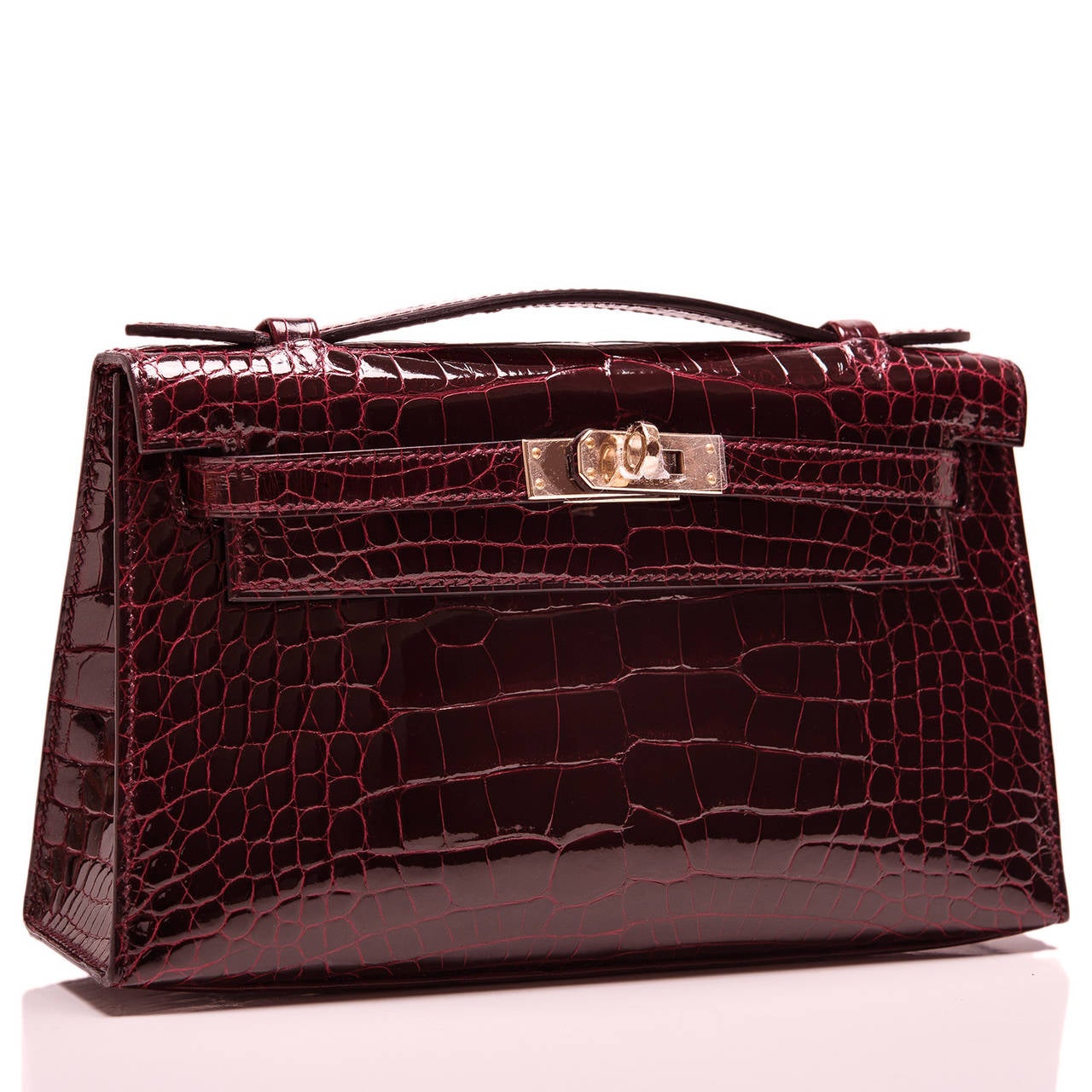 Hermes Bordeaux Shiny Alligator Kelly Pochette clutch with permabrass hardware.

This Hermes Kelly Pochette features tonal stitching, a front flap with two straps, toggle closure and single flat handle. The interior is lined in Bordeaux chevre and