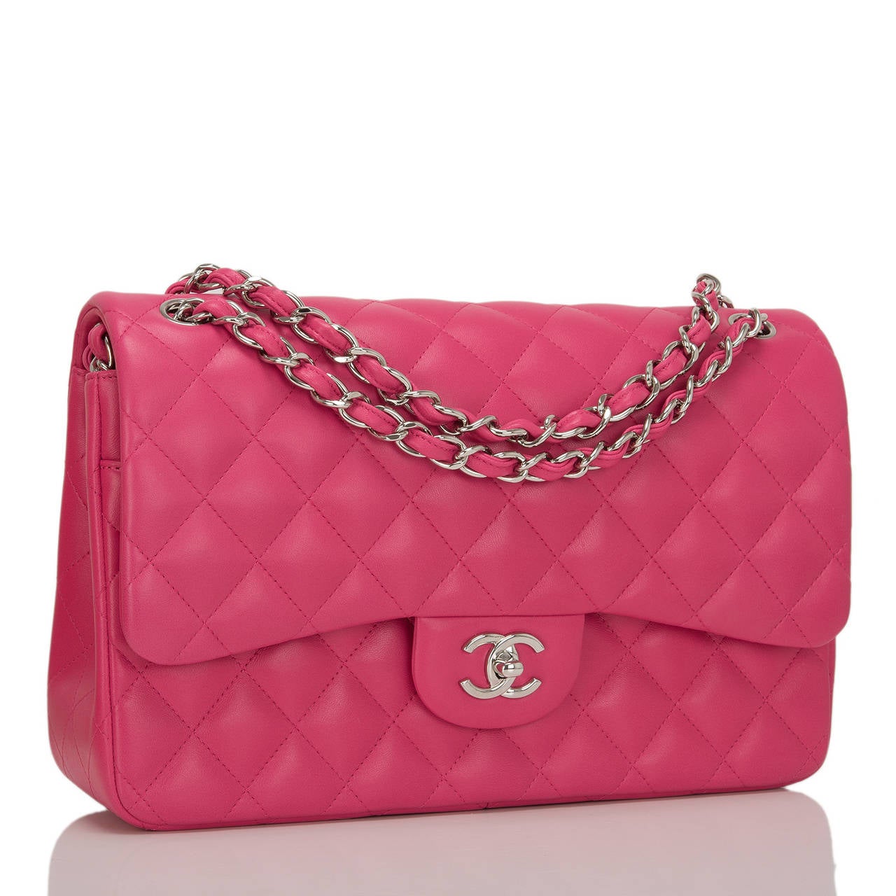 This Chanel Jumbo Classic double flap of limited edition fuchsia pink lambskin leather with silver tone hardware features a front flap with signature CC turnlock closure, half moon back pocket, and an adjustable interwoven silver tone chain link and