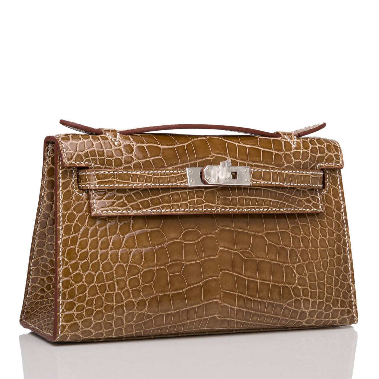 Hermes Ficelle Shiny Alligator Mini Kelly Pochette clutch with palladium hardware.

This Hermes Kelly Pochette features contrastl stitching, a front flap with two straps, toggle closure and single flat handle. The interior is lined in Ficelle