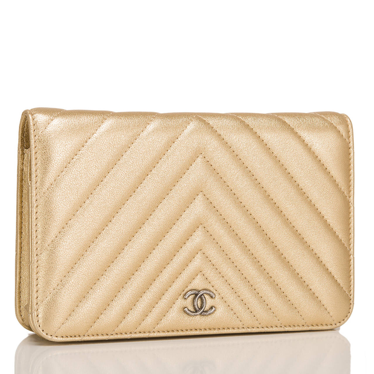 This Gold Quilted Chevron WOC in gold lambskin leather features signature Chanel Chevron quilting and ruthenium hardware,a front flap with CC charm and hidden snap closure, expandable sides and bottom, half moon rear pocket and interwoven ruthenium