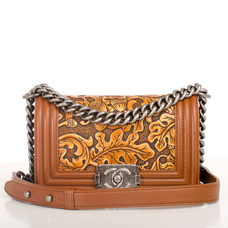 Chanel brown cordoba leather Small Boy Bag

This styles features ornate autumnal leaf and acorn motif, ruthenium hardware, and front flap with CC push lock closure and ruthenium chain link and brown leather padded shoulder strap.

Interior is