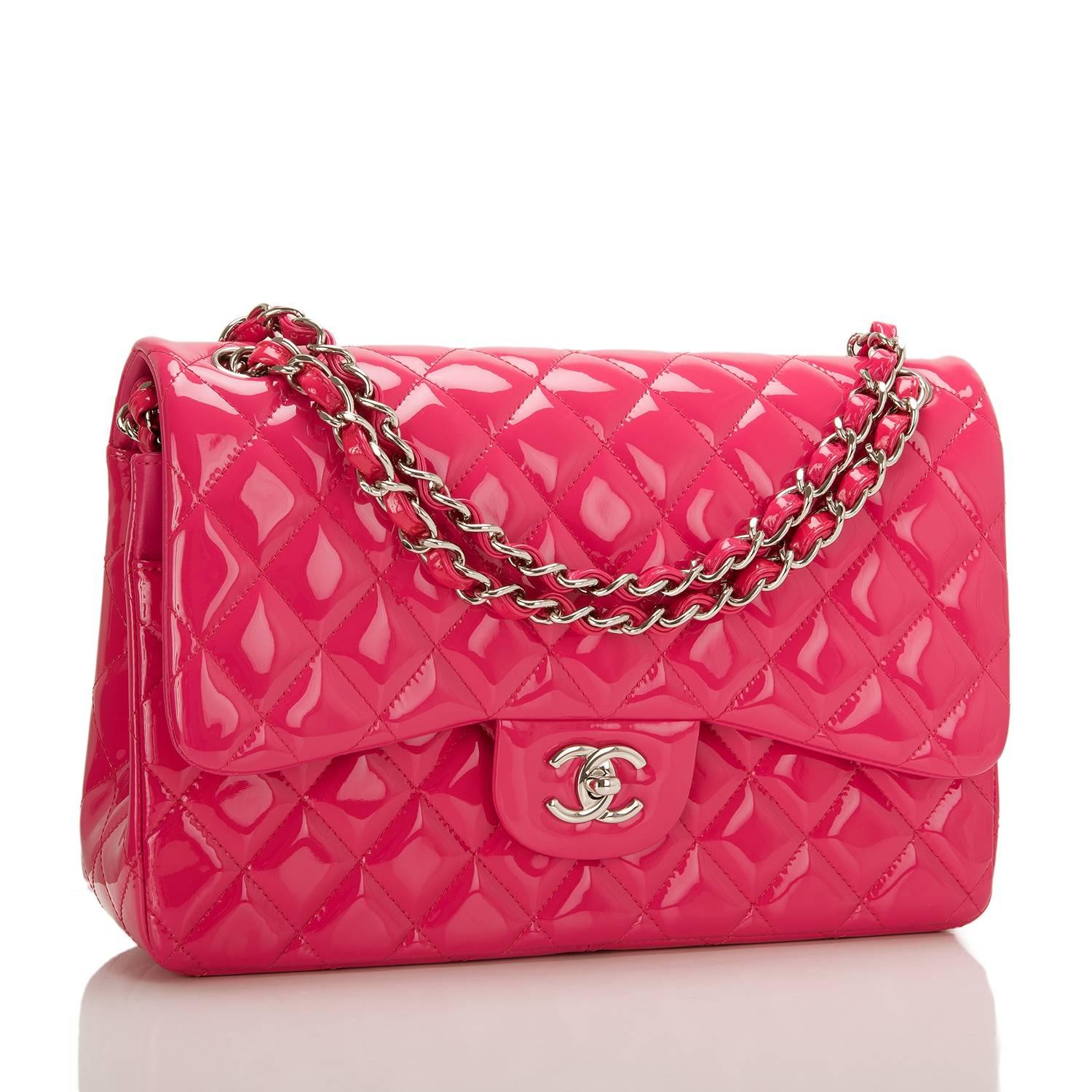 Chanel Jumbo Classic double flap bag of fuchsia pink patent leather with silver tone hardware.

This bag features a front flap with signature CC turnlock closure, a half moon back pocket, and an adjustable interwoven silver tone chain link with