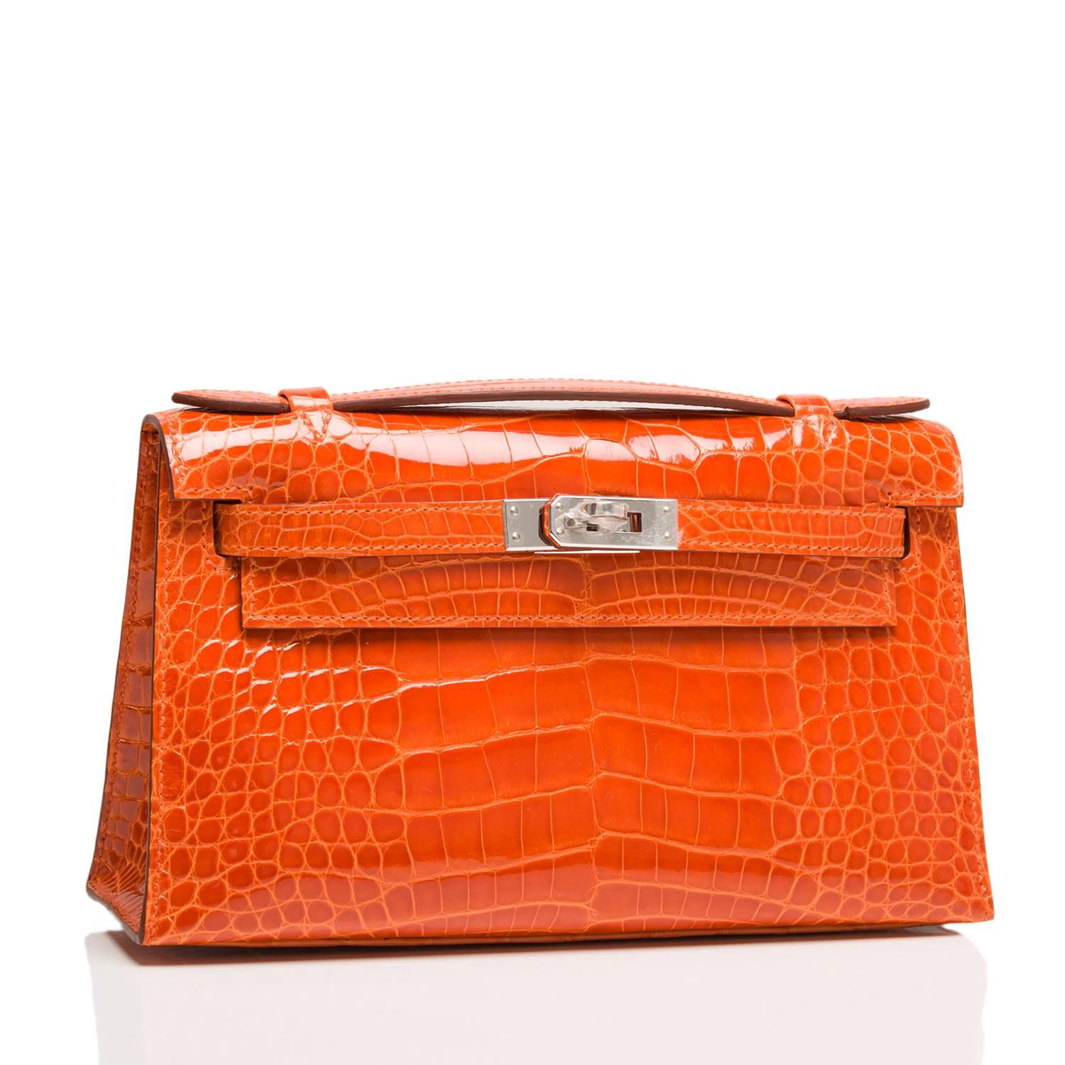  	
Hermes Orange H Shiny Alligator Mini Kelly Pochette clutch with palladium hardware.

This Hermes Kelly Pochette features tonal stitching, a front flap with two straps, toggle closure and single flat handle.

The interior is lined in Orange H