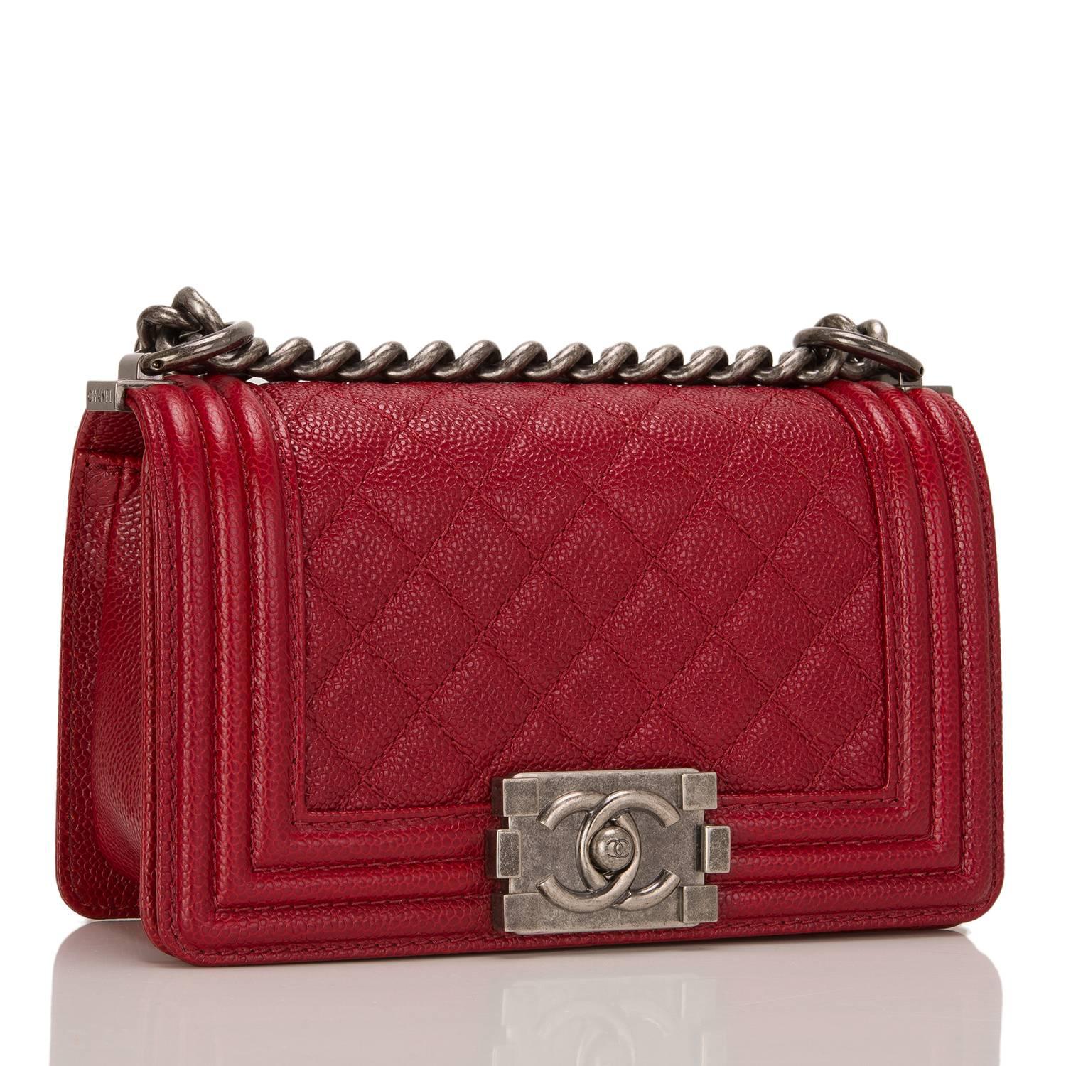 Chanel Small Boy bag in dark red caviar leather with aged ruthenium hardware.

This bag has a front flap with Le Boy CC push lock closure, and aged ruthenium chain link and red leather padded shoulder strap.

The interior is lined in red fabric