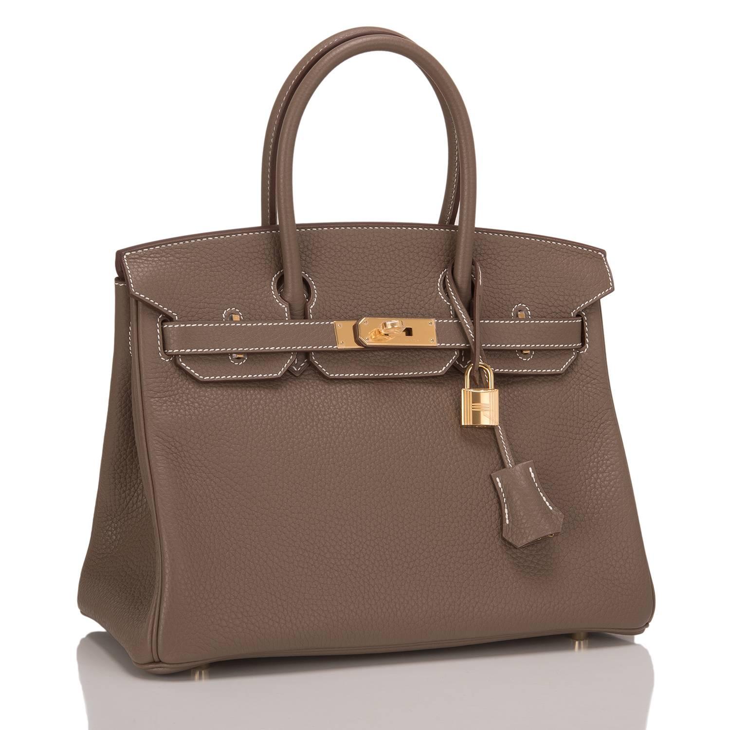 Hermes Etoupe 30cm in clemence leather with gold hardware.

This Birkin features tonal stitching, front toggle closure, clochette with lock and two keys, and double rolled handles. The interior is lined in Etoupe chevre with one zip pocket with an