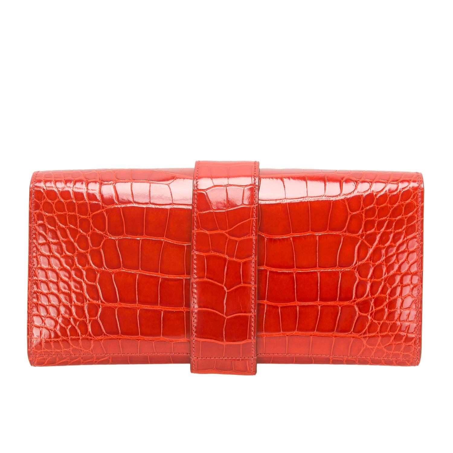  	
Hermes Sanguine Medor 23cm clutch in shiny alligator with gold hardware.

This rare Hermes style features tonal stitching, front flap, gold studded hardware, and an adjustable wrap around gold metal closure.

The interior is lined in