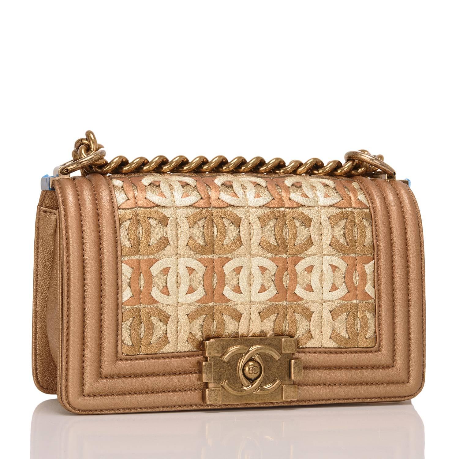 This Chanel CC embellished small Boy bag is made of dark gold metallic lambskin leather and accented with antique gold tone hardware. The bag features multi-tone metallic gold laser-cut CC logos intertwined in the body of the bag turning the CC