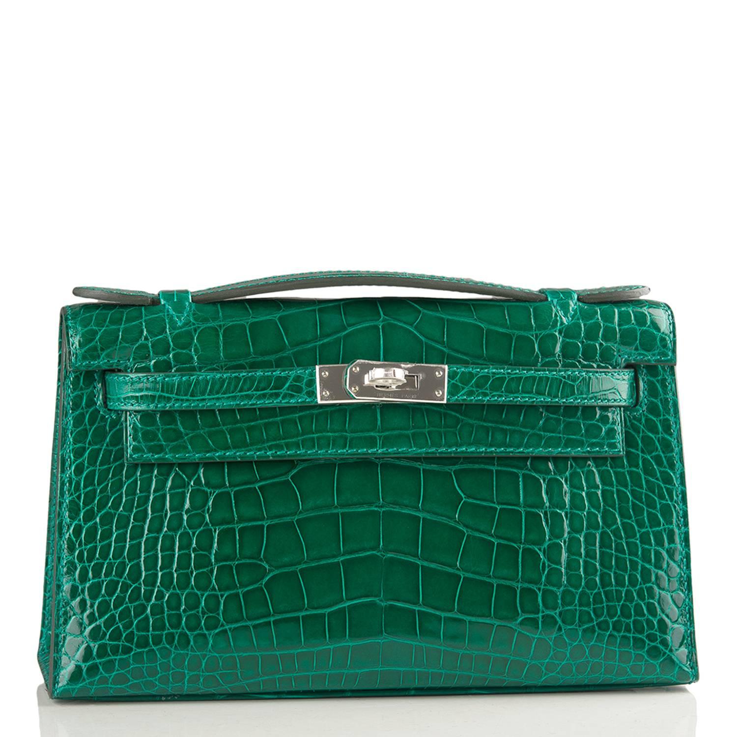 Hermes Mini Kelly Pochette clutch of Emerald (Emeraude) Shiny Alligator with palladium hardware.

This Hermes Kelly Pochette has tonal stitching, a front flap with two straps, a toggle closure and a single flat handle.

The interior is lined with