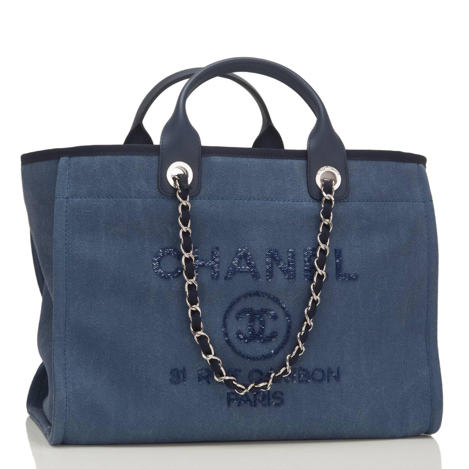 Chanel Large Deauville Canvas Tote of navy canvas with navy sequin accents and silver tone hardware.

This bag features the signature CC logo in a circle with the brand CHANEL above it and the Paris flagship store address -- 