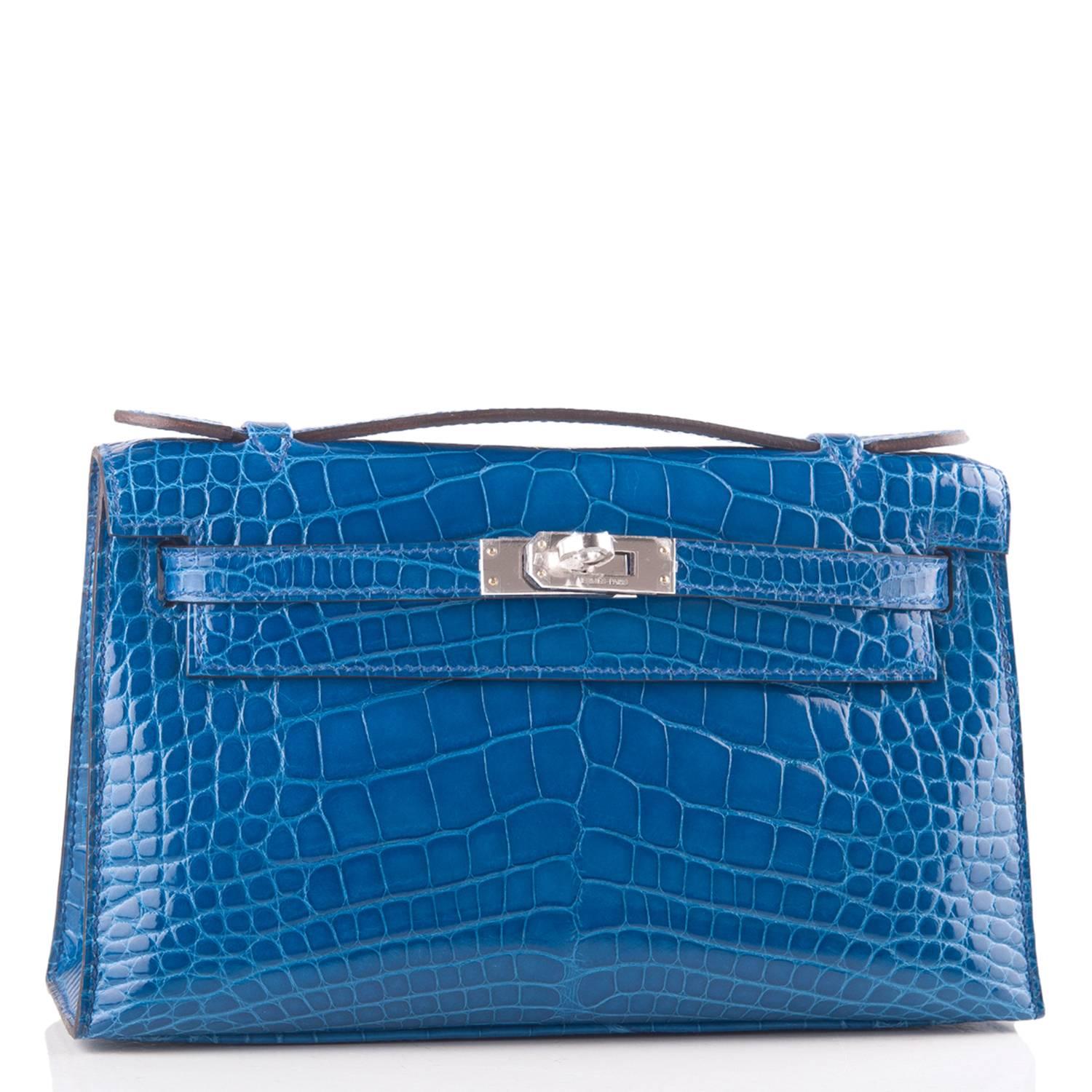 Hermes Mini Kelly Pochette clutch of Mykonos Shiny Alligator with palladium hardware.

This Hermes Kelly Pochette has tonal stitching, a front flap with two straps, a toggle closure and a single flat handle.

The interior is lined with Mykonos