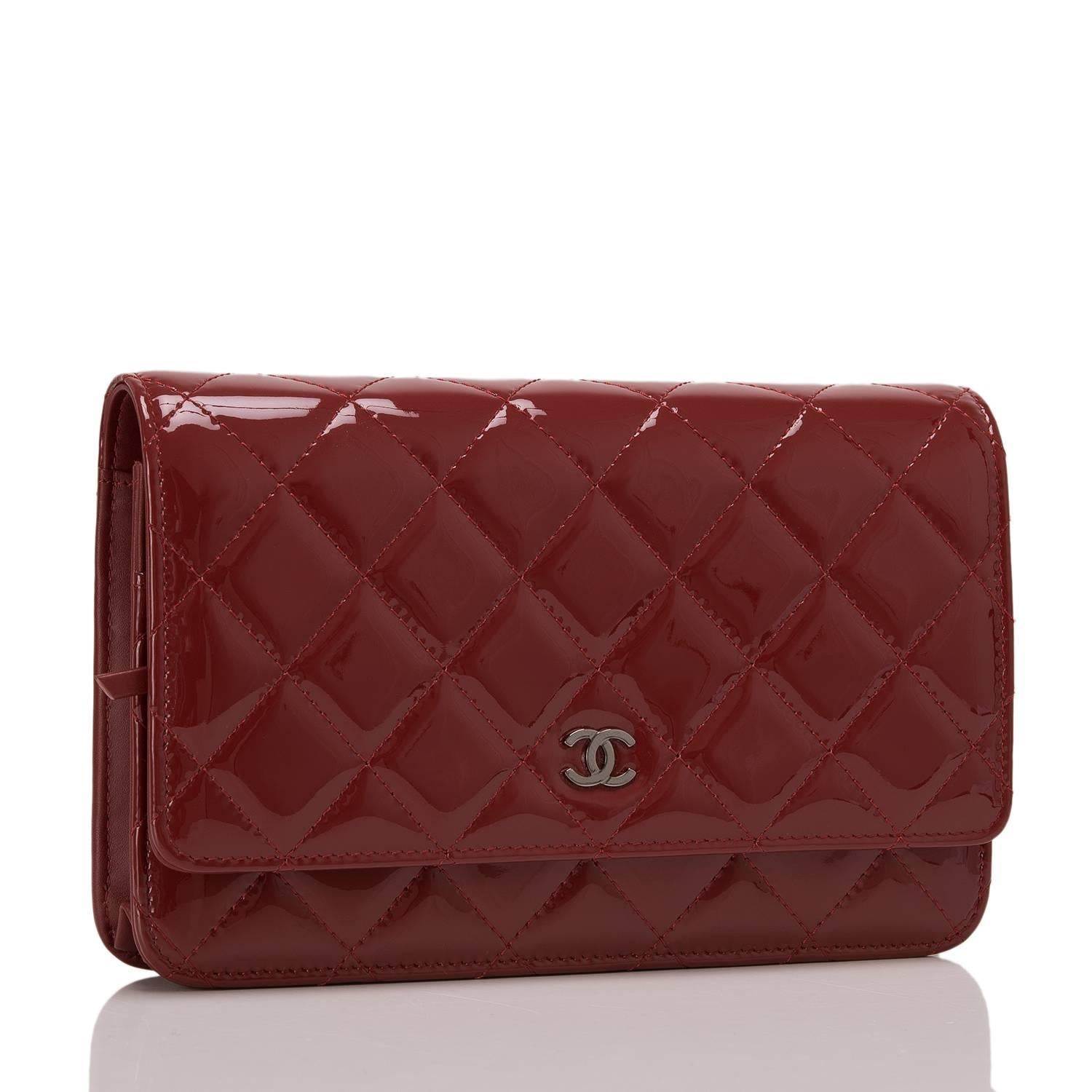 This dark red quilted patent timeless WOC with ruthenium hardware features signature Chanel quilting, front flap with CC charm and hidden snap closure, expandable sides and bottom, half moon rear pocket and interwoven ruthenium chain and leather