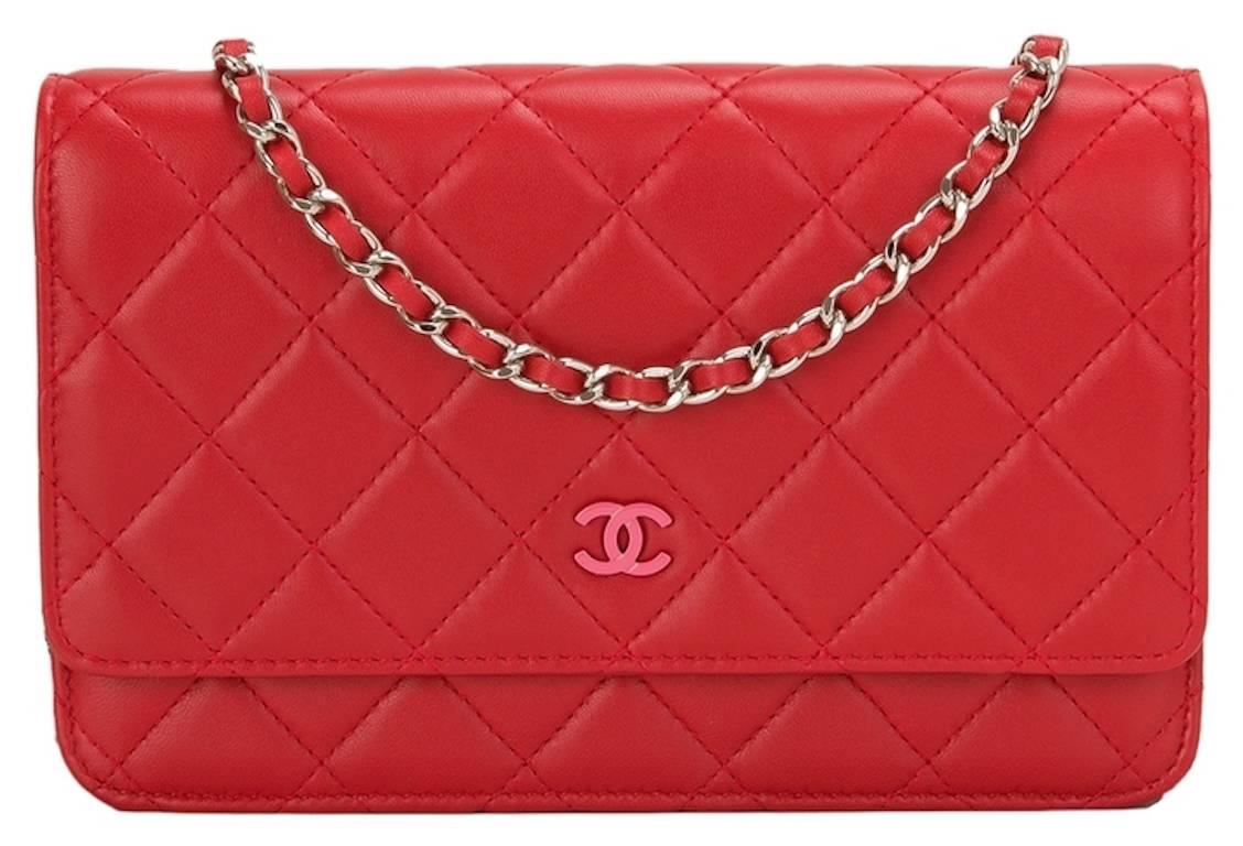 Chanel Wallet On Chain (WOC) of quilted red lambskin leather with silver tone hardware and pink CC charm.

This limited edition WOC has a front flap with a pink CC closure and hidden snap closure, a half moon rear pocket, and an interwoven silver