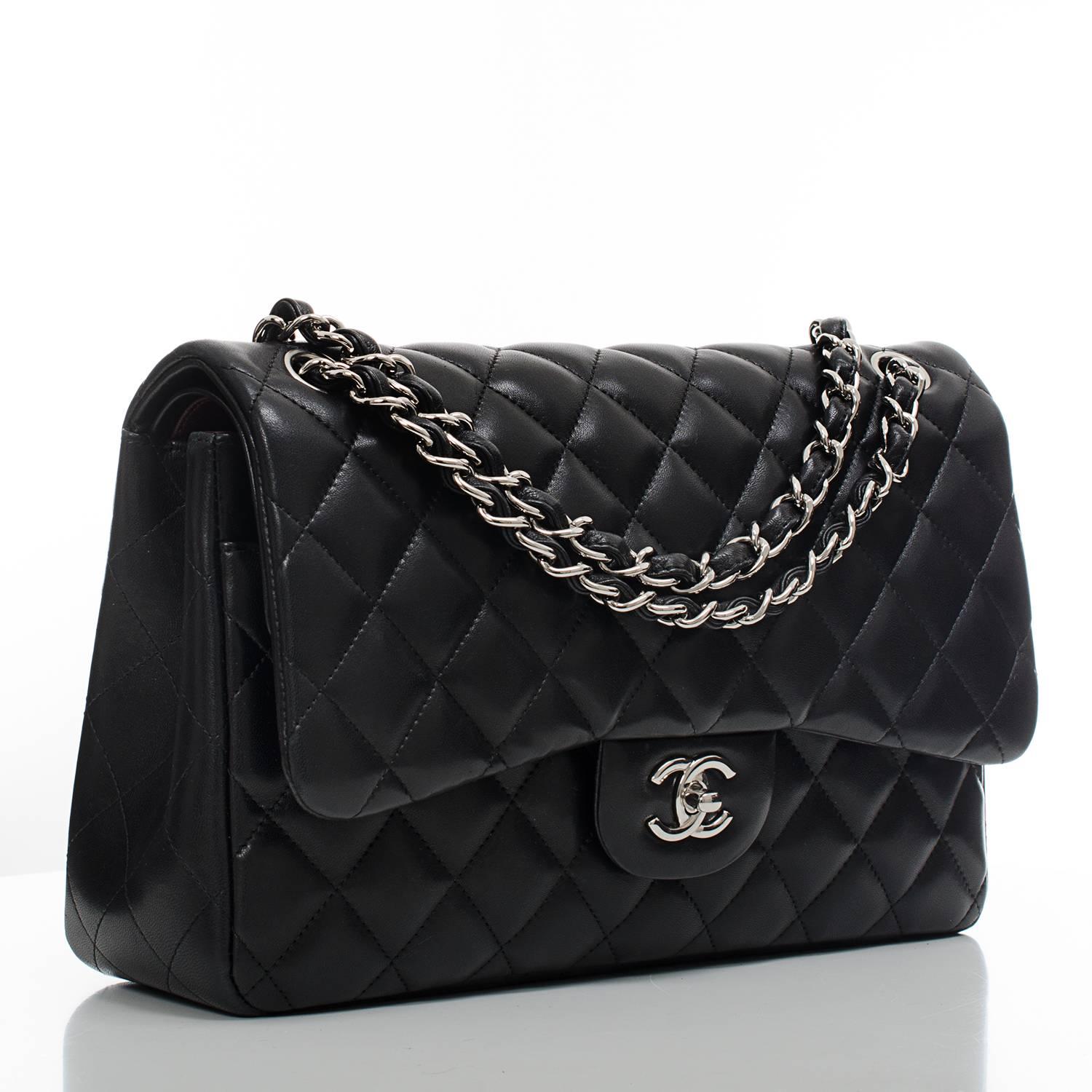 Chanel Jumbo Classic double flap of black lambskin with silver tone hardware featuring front flap with signature CC turnlock closure, half moon back pocket, and adjustable interwoven silver tone chain link and black leather shoulder strap.

The