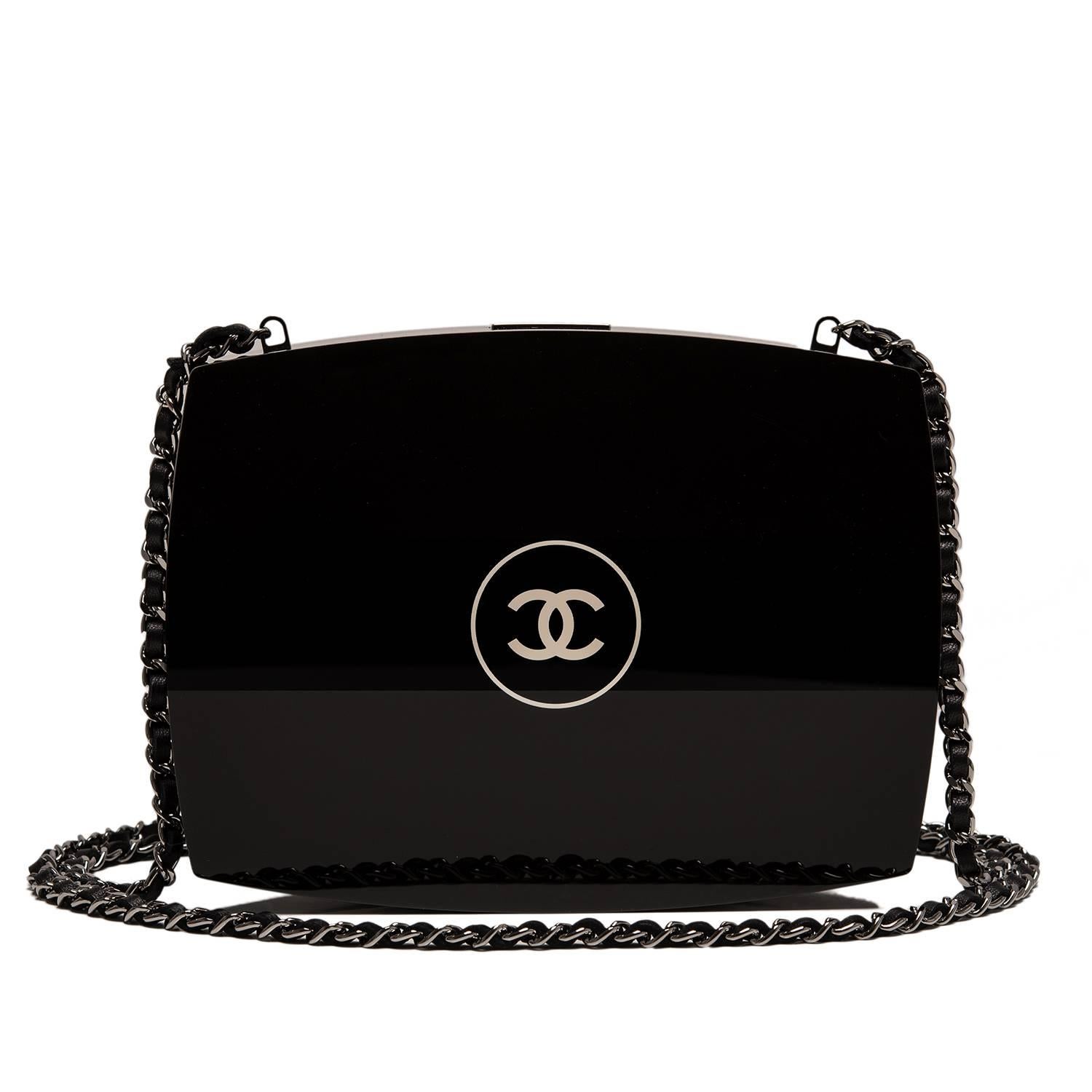 This Chanel Compact Powder Minaudière is made of black plexiglass with silver tone metal hardware.

It features Chanel's signature CC logo in circle on front, CHANEL engraved top snap closure, and interwoven silver tone chain link and black